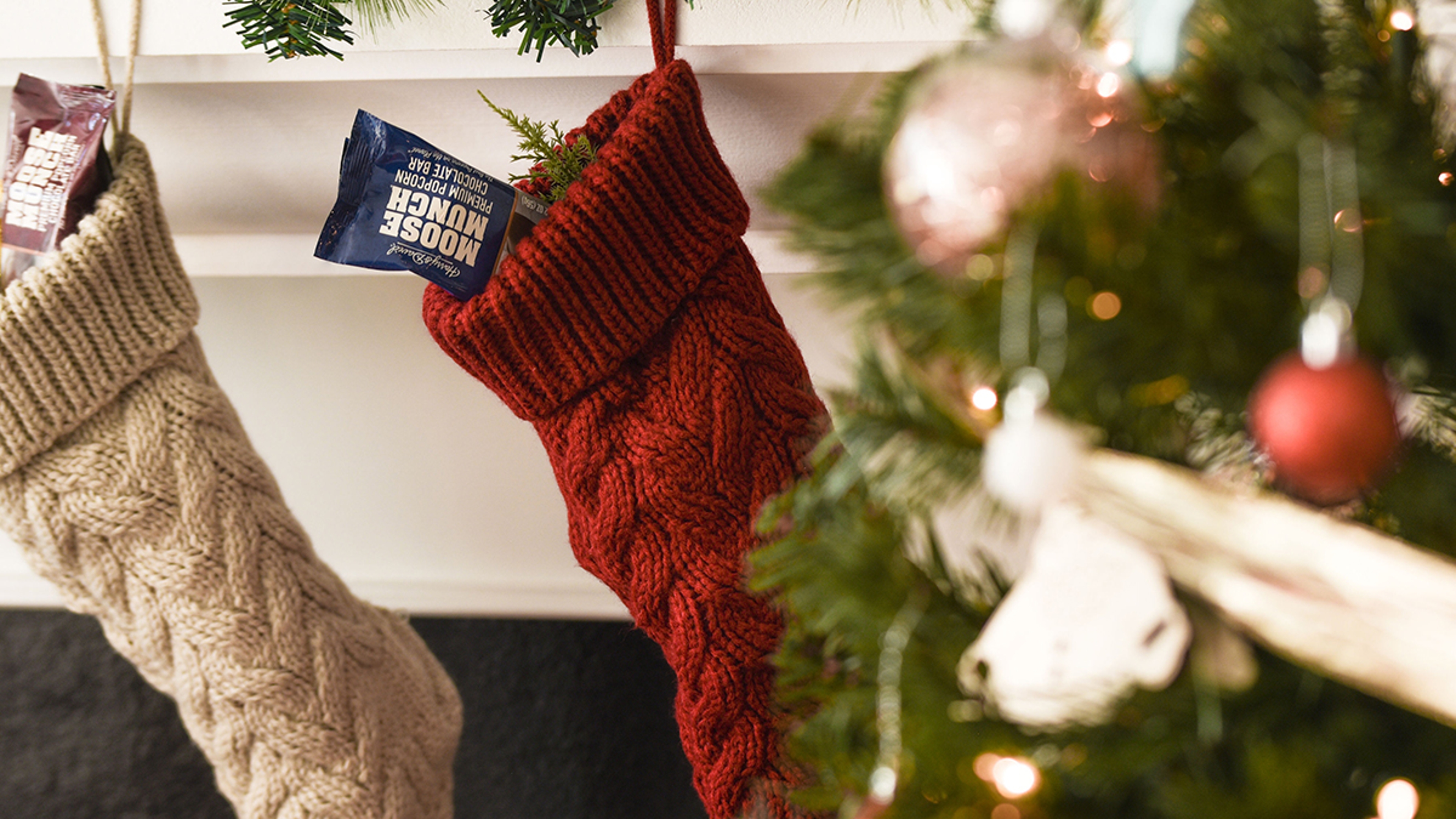 Stockings hanging on a mantel piece with candy poking out of them.