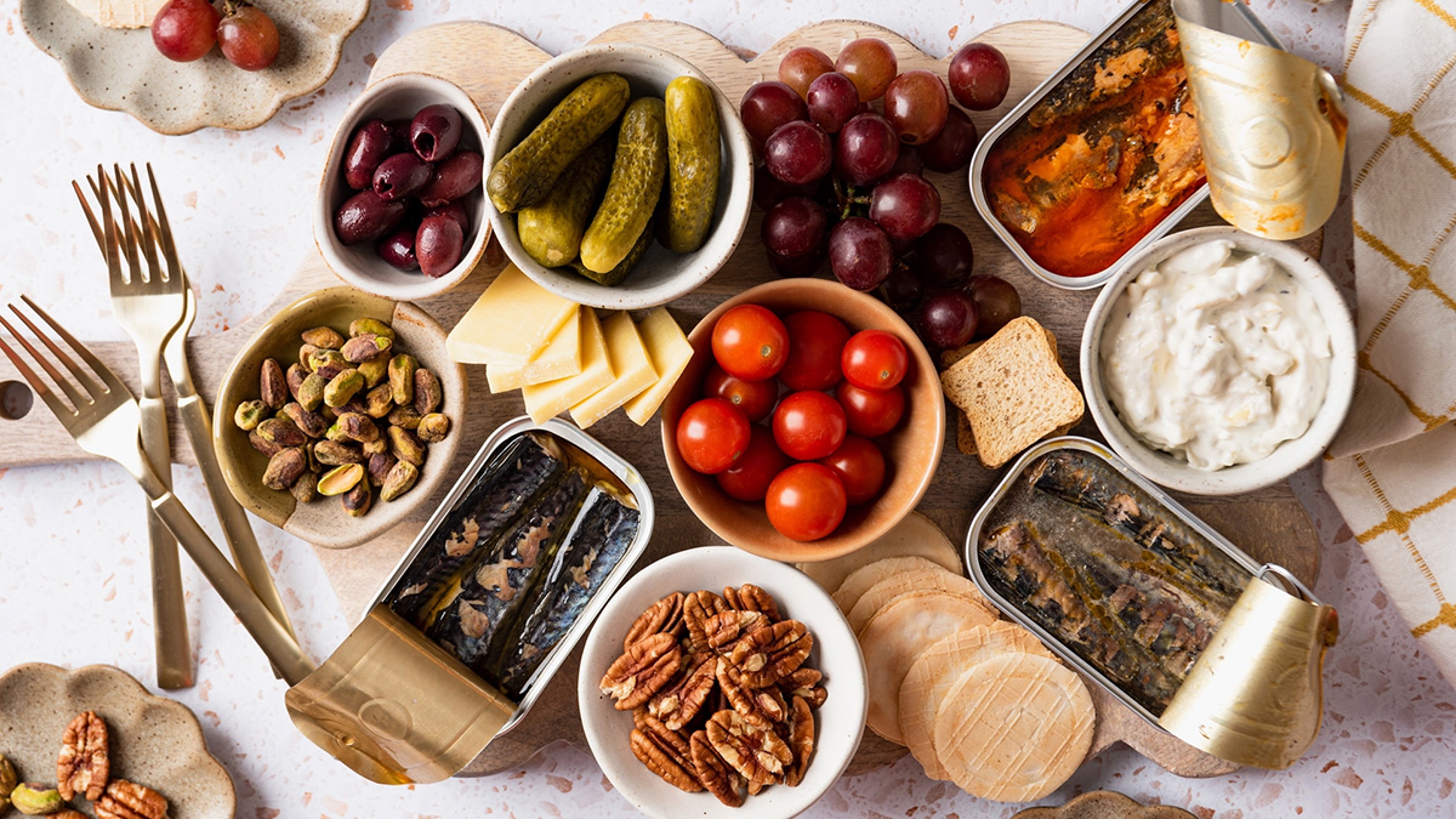 Seacuterie board with tinned fish, vegetables, and cheese.