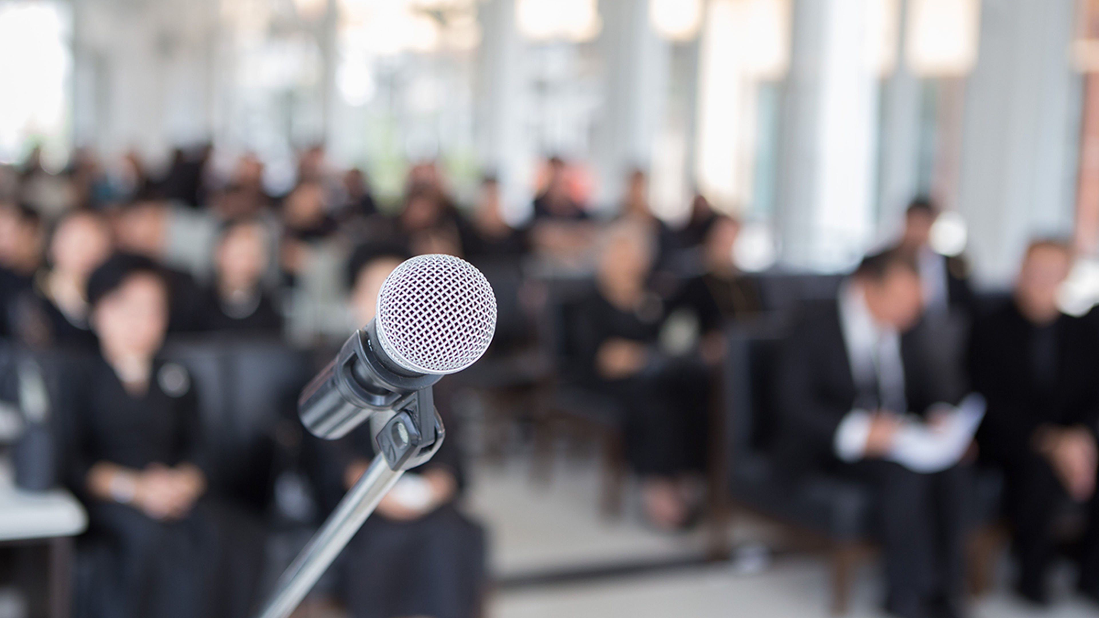 Article Cards Featured Image Microphones on the funeral podium and people wearing black in the church