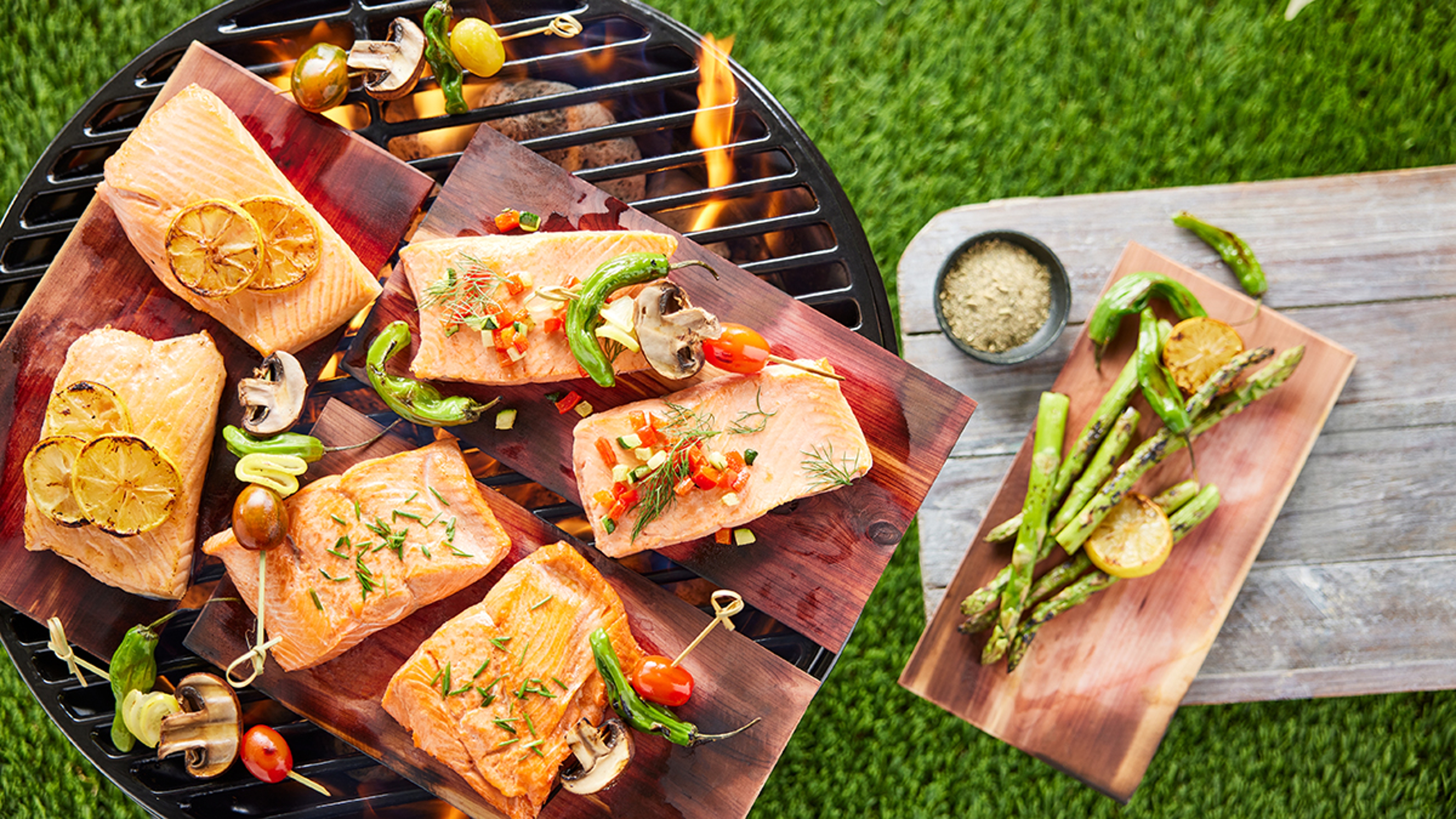 Cedar plans topped with fish on top of a grill.