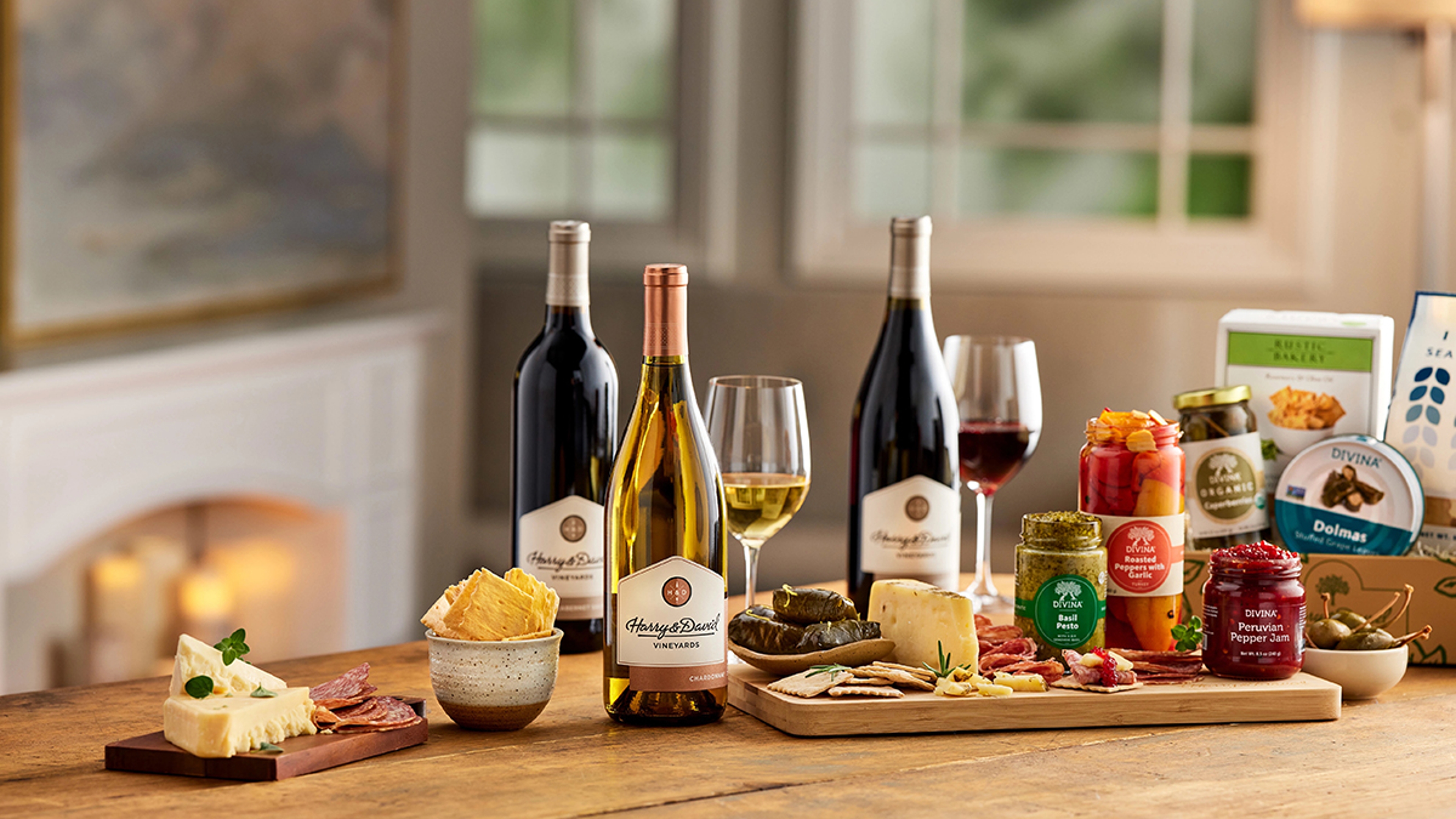 Bottles from the wine shop on a table surrounded by cheese and other snacks.