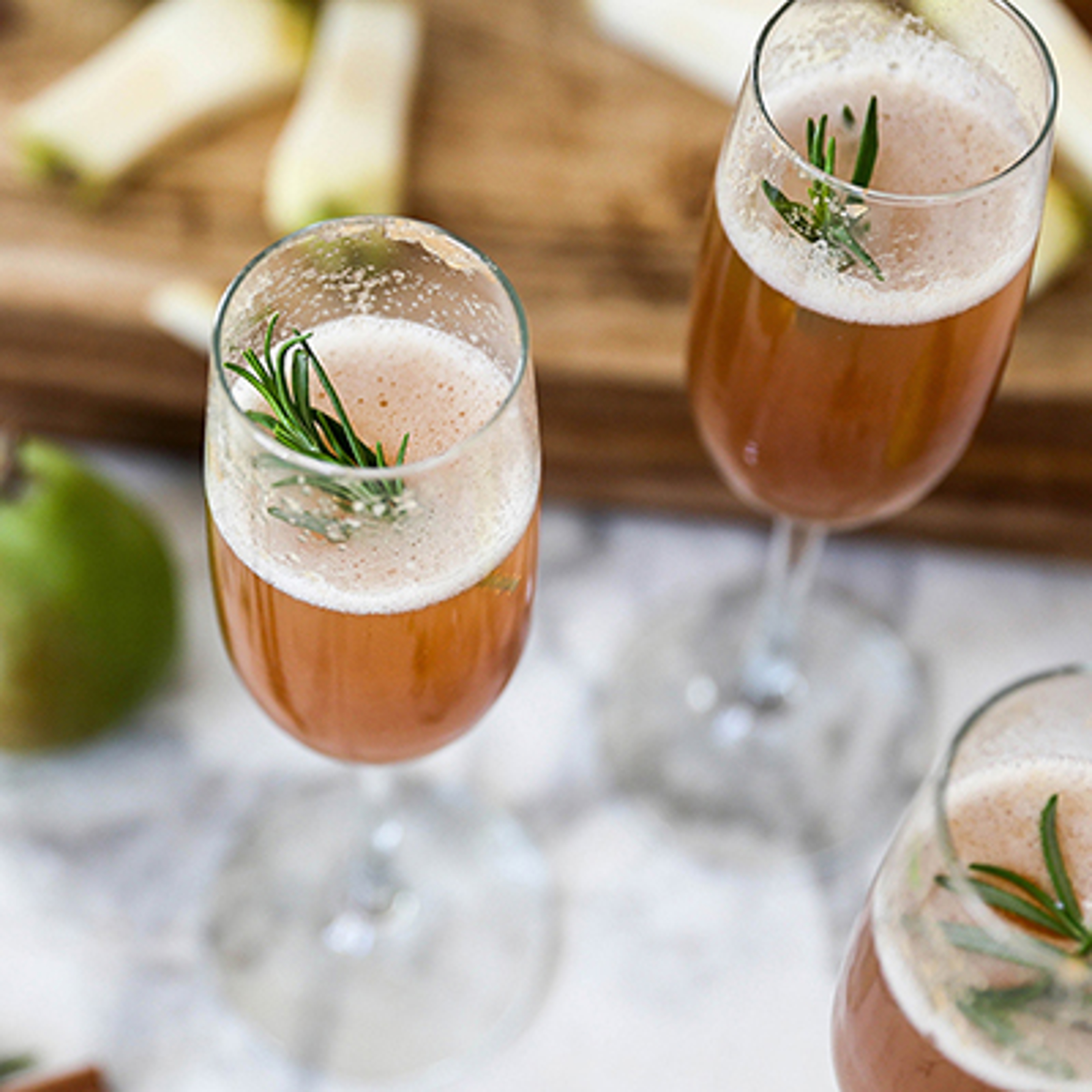 Two pear Bellinis with rosemary garnishes.