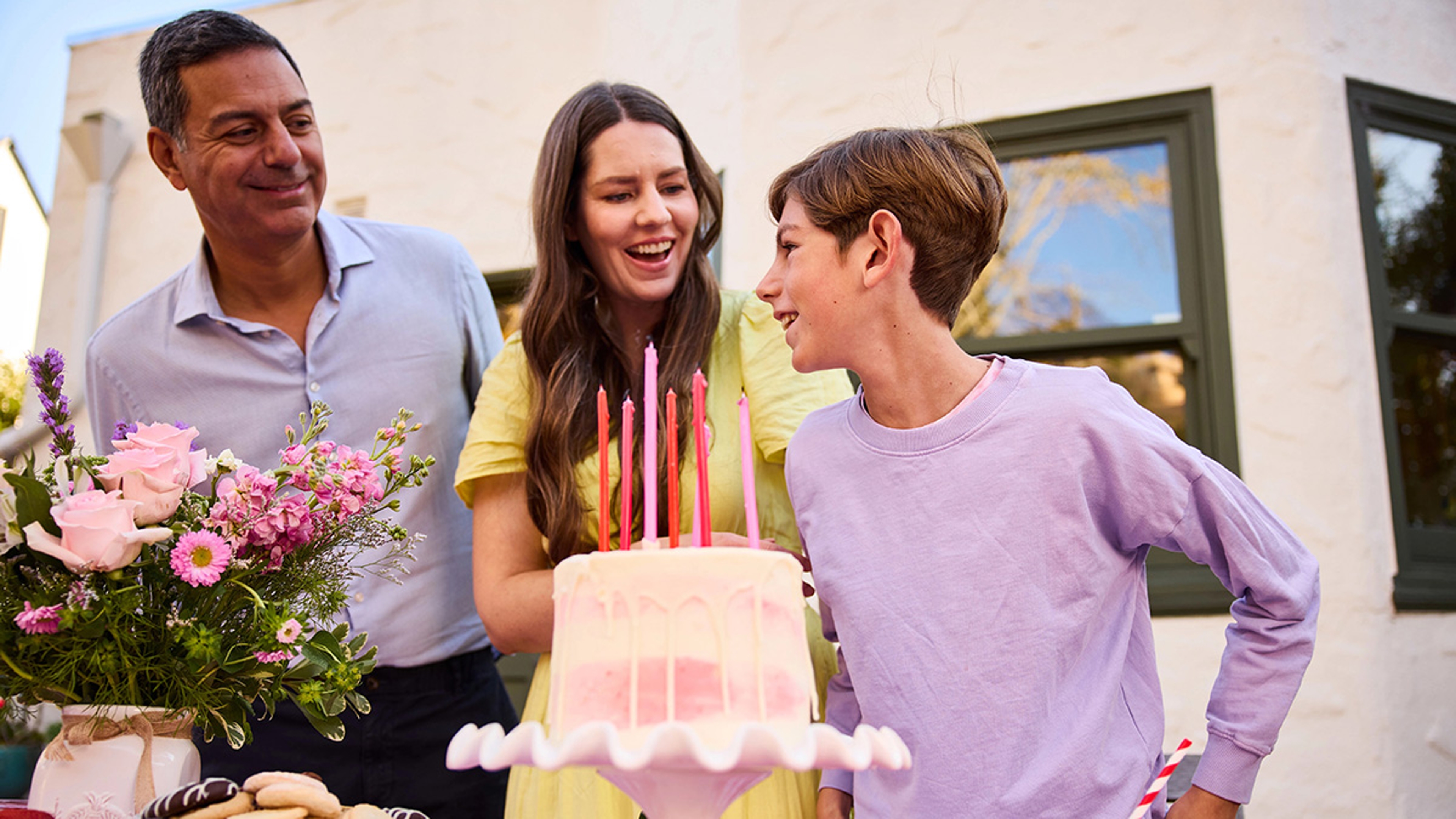 Family singing happy birthday to son.
