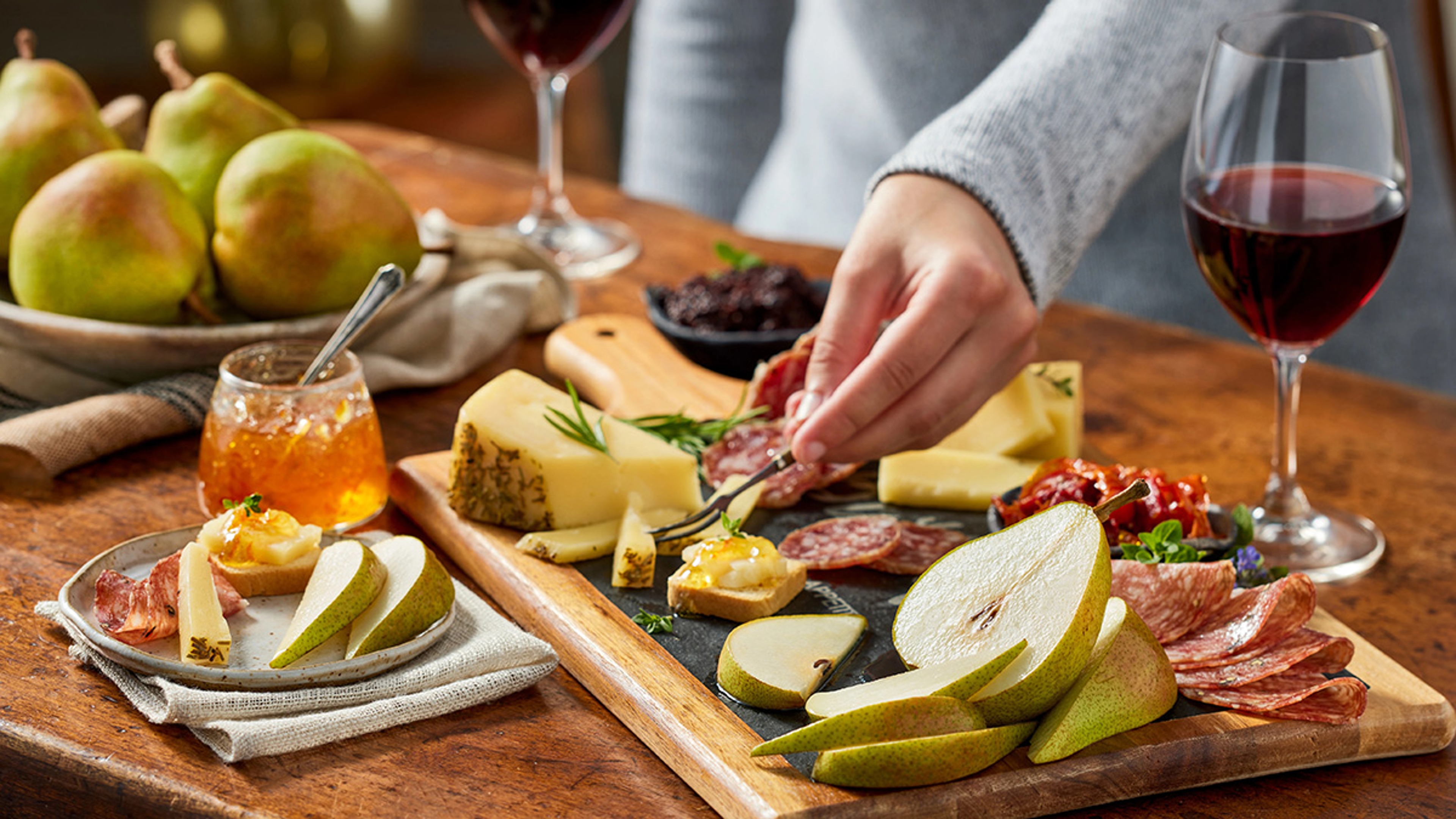Spread of charcuterie, fruit, and cheese with glasses of wine.