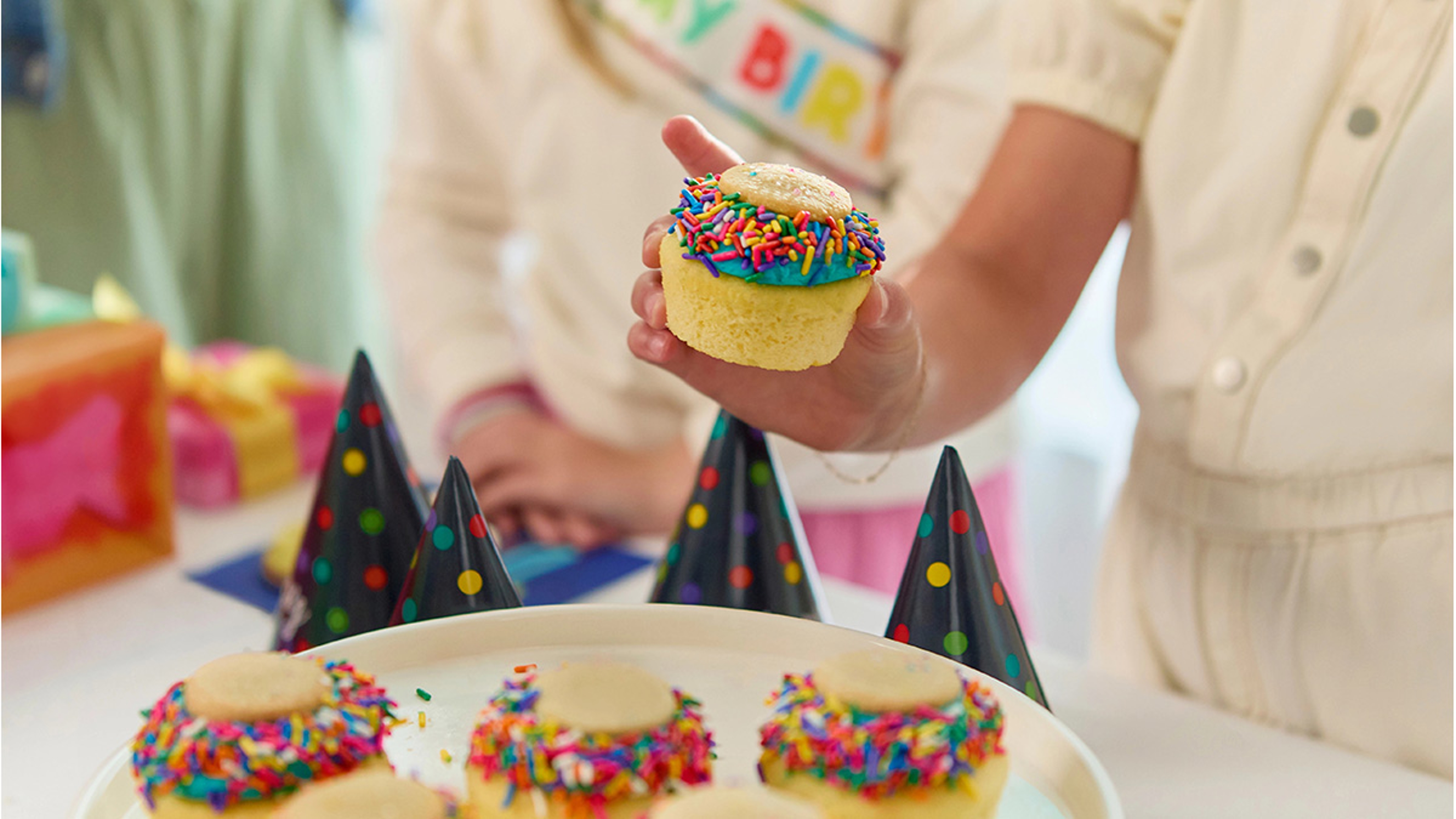 Young girl picking up a cupcake as a birthday cake alternative at a party.