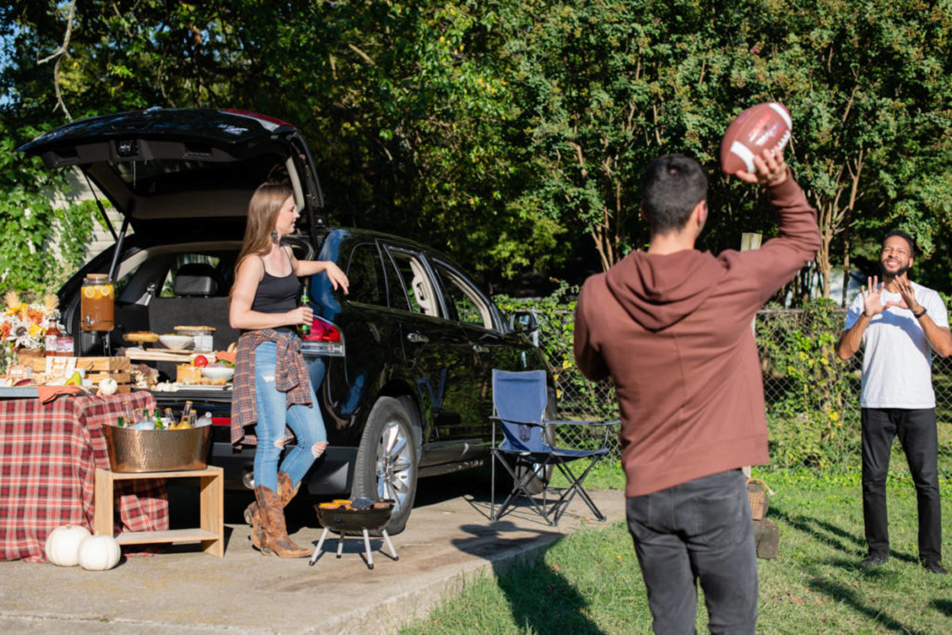 Tailgate party with men throwing a football.