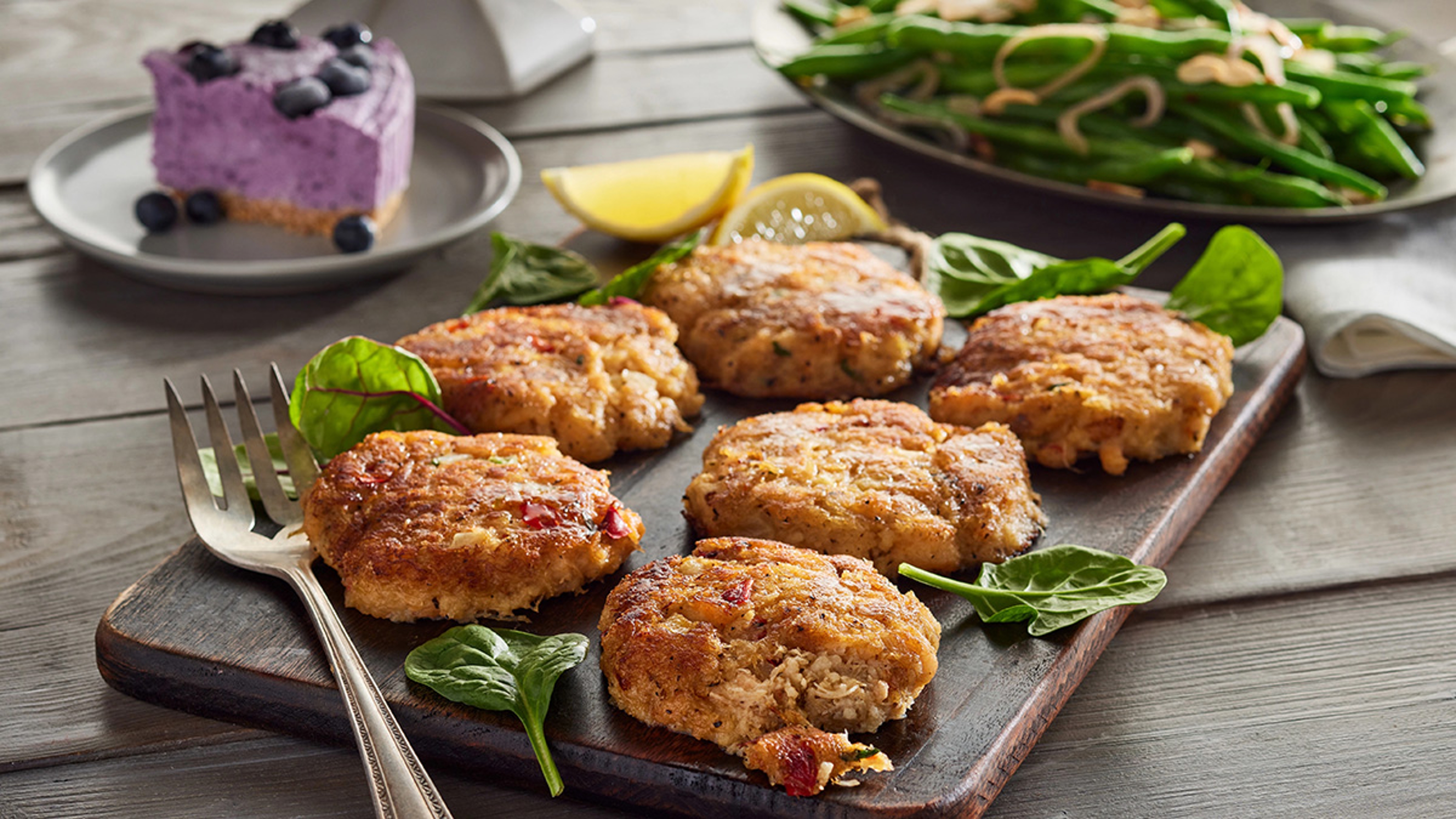 Crab cakes with lemon slices and greens.