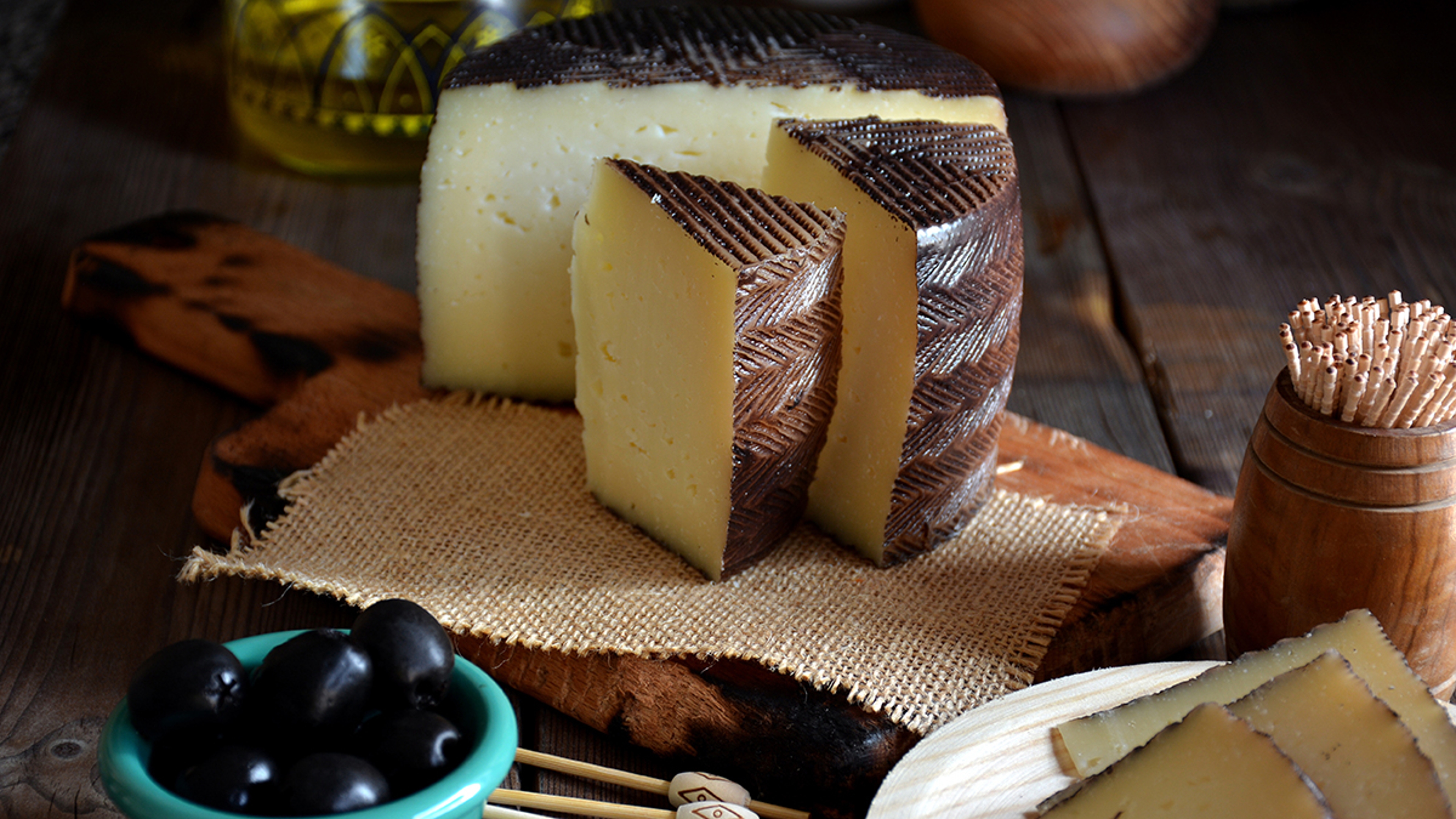 types of cheese pieces of manchego cheese on a wooden table accompanied by olives