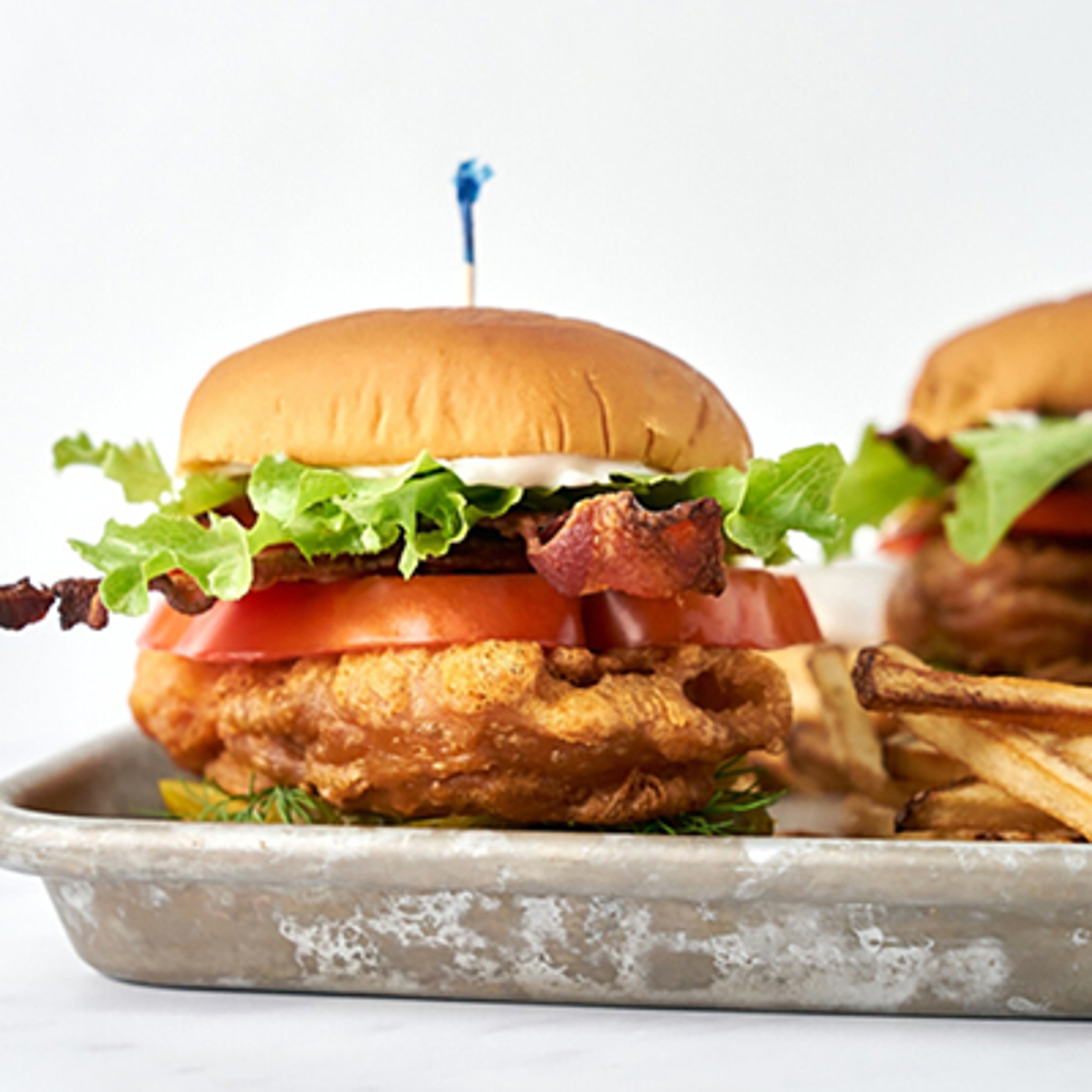 Two cod BLTs on a tray.