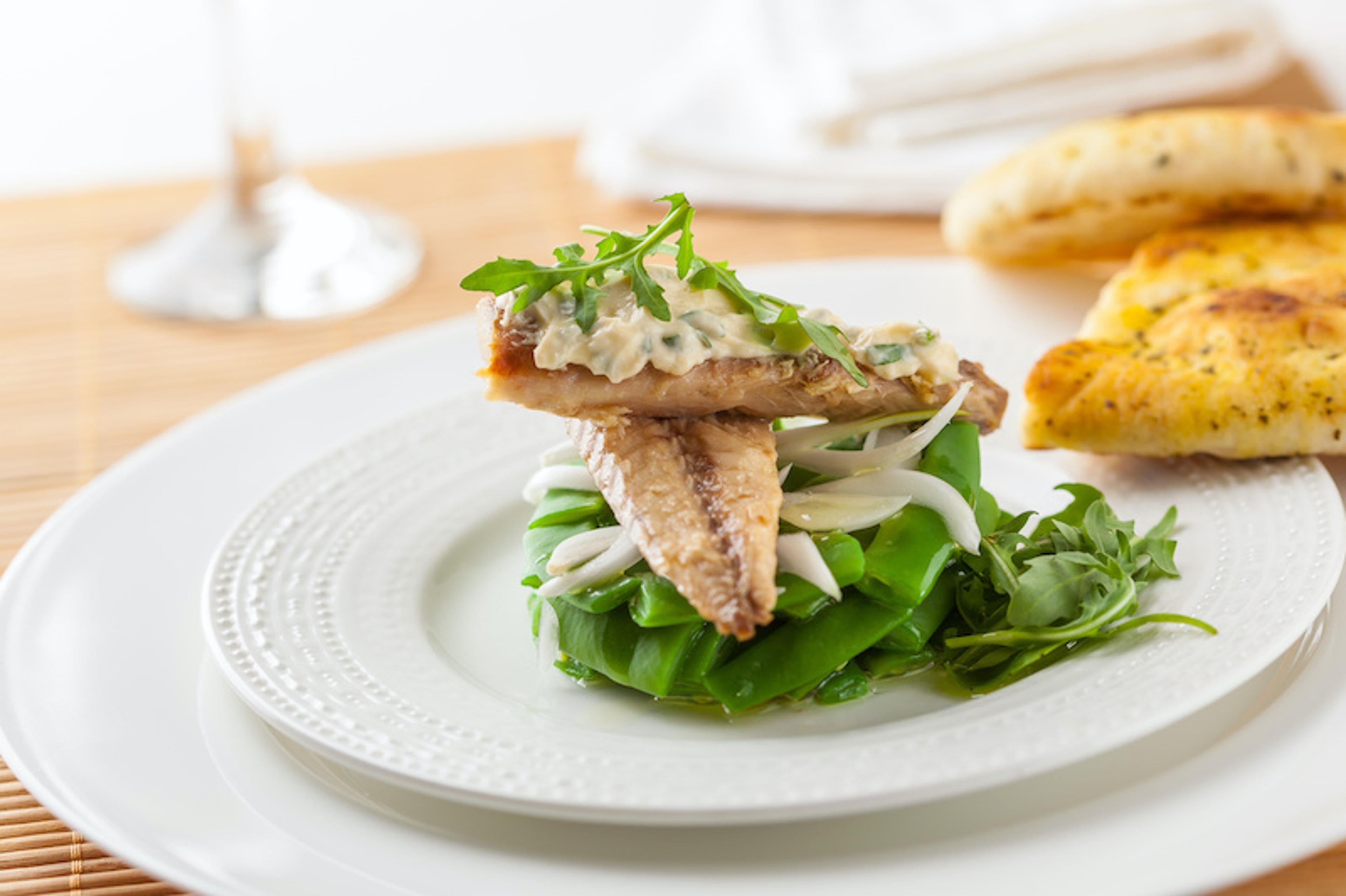 mackerel on a plate ontop of green beans and arugula