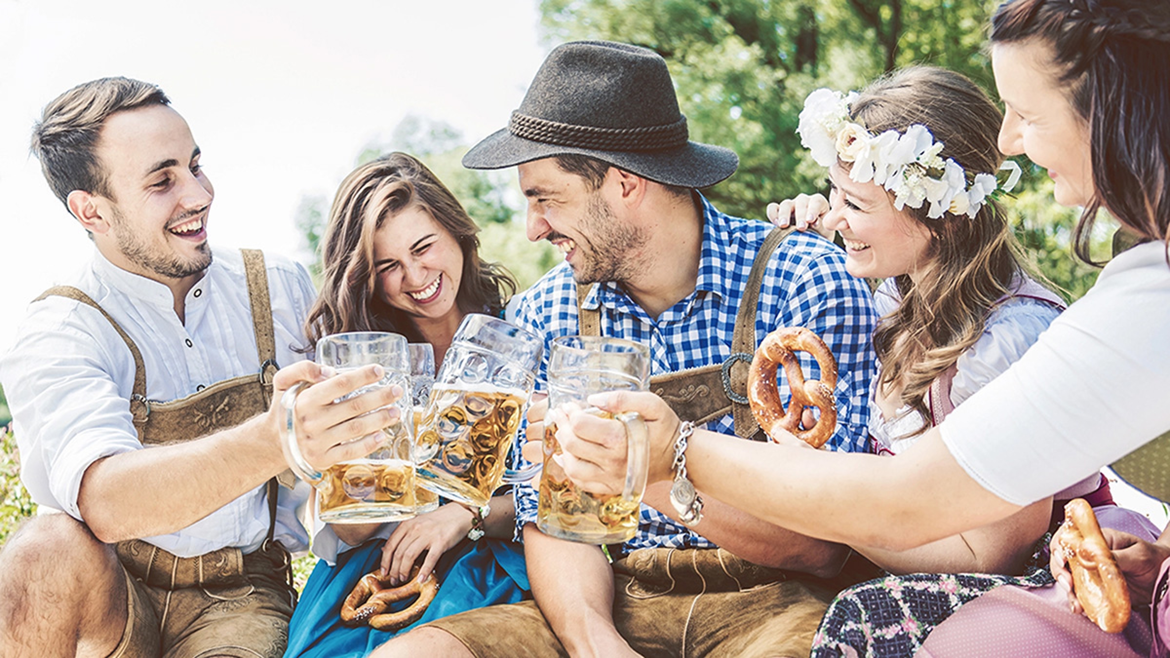 Group of adults celebrating Oktoberfest with beer and pretzels.
