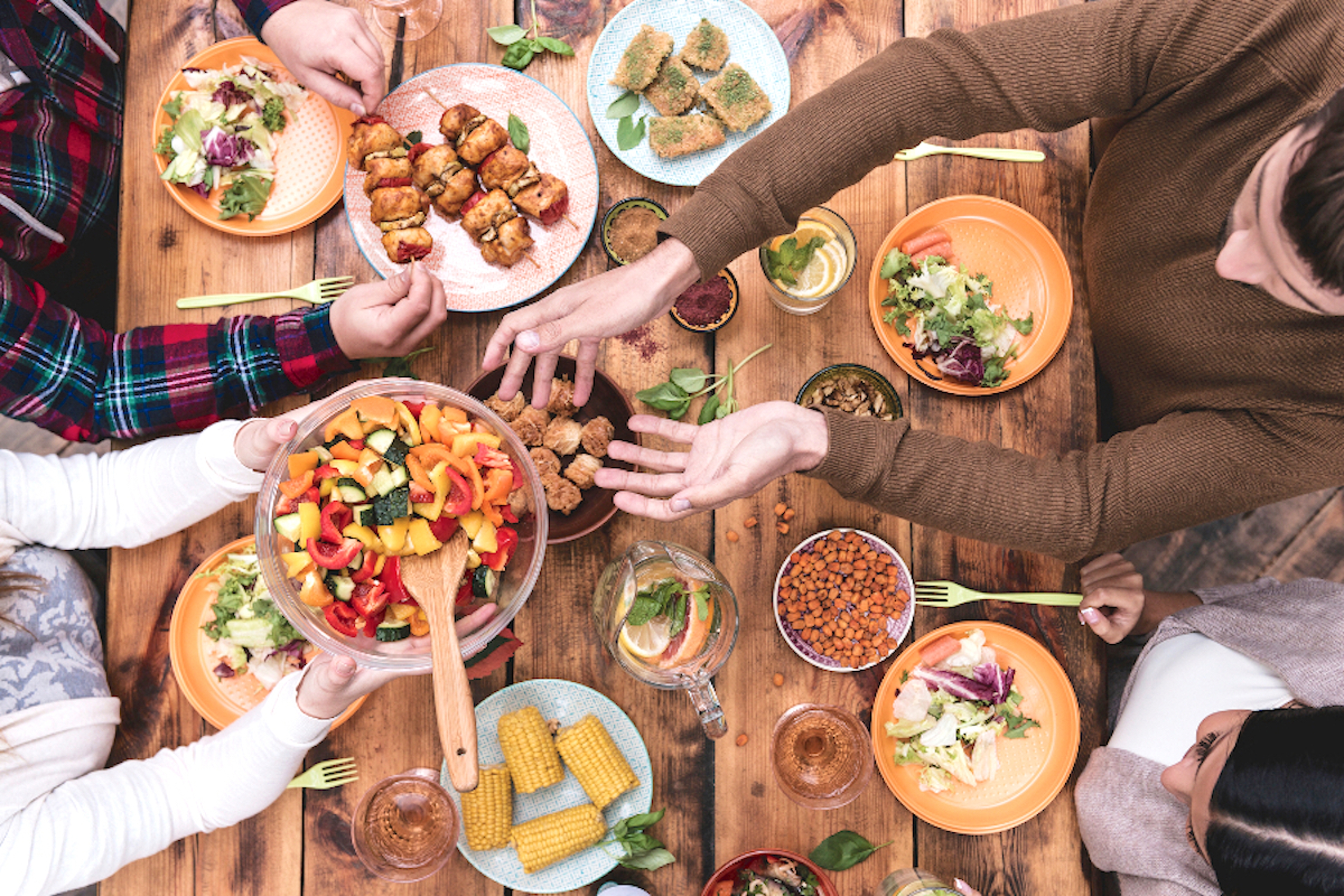 Article Cards Featured Image Friends having dinner. Top view of four people having dinner together while sitting at the rustic wooden table