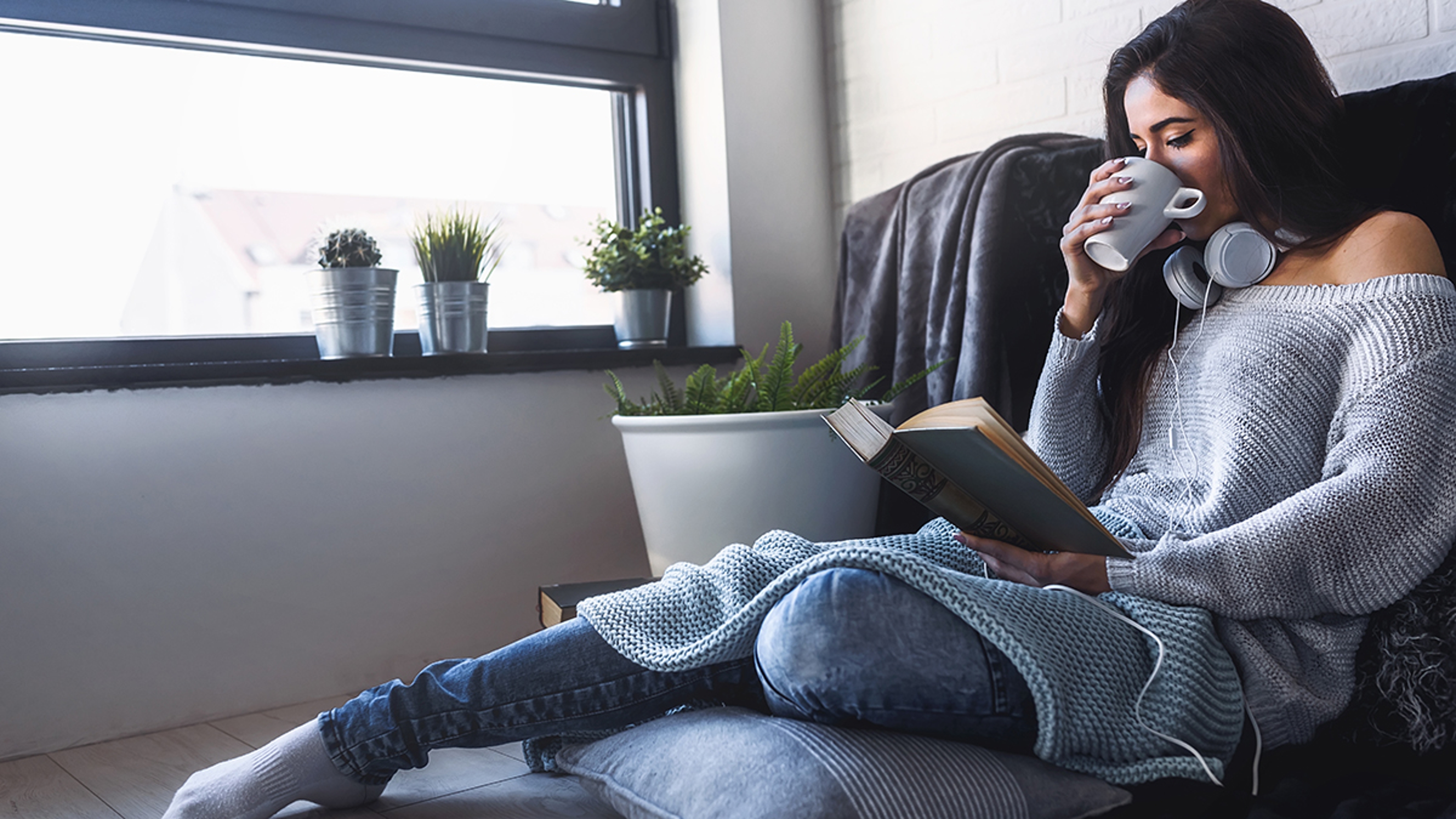 Virgo woman reading a book and drinking a cup of coffee.