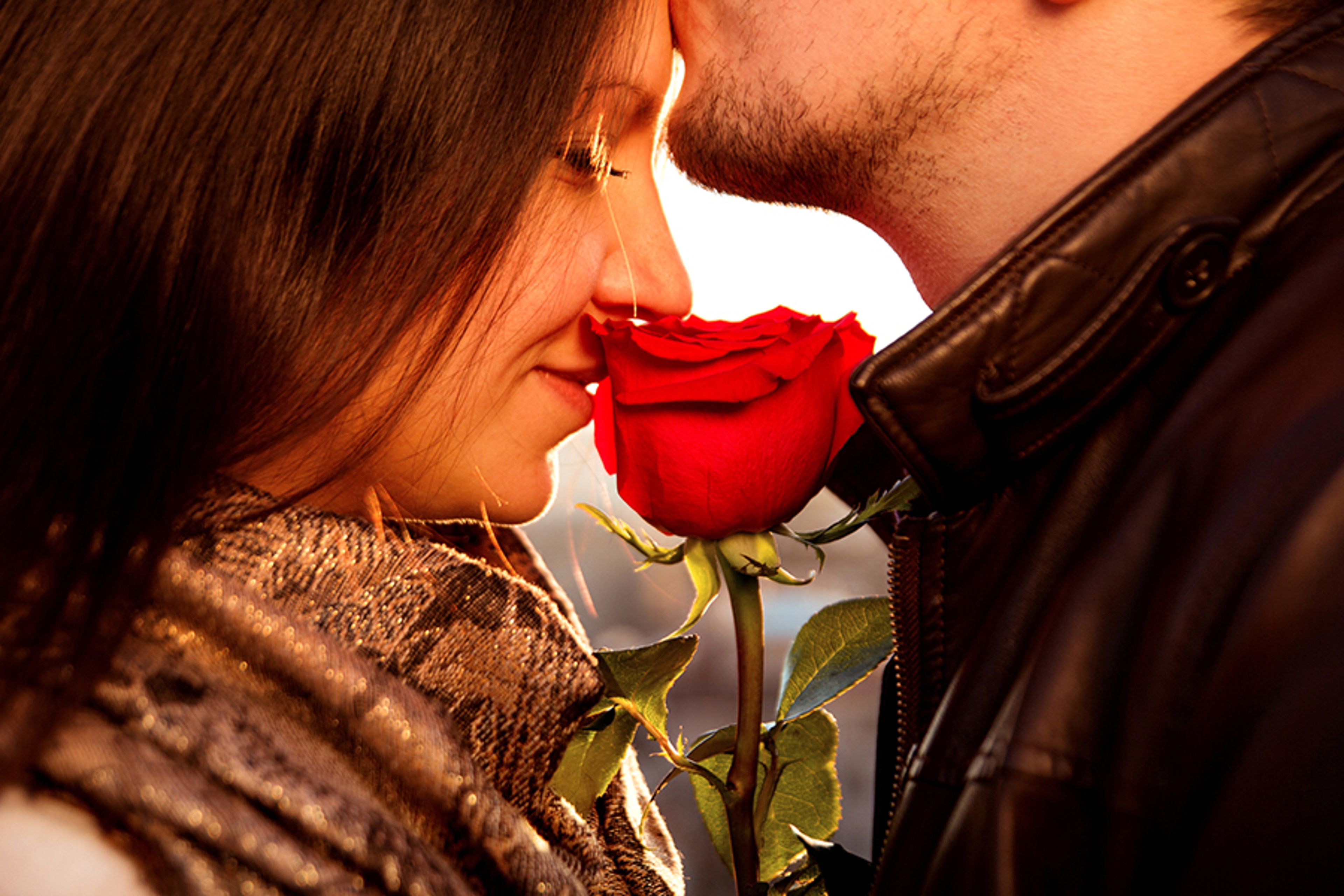 Article Cards Featured Image Happy and loving couple for Valentine's Day. Amorous guy gently kissing his girl in the forehead while she is enjoying the smell of the magnificent red rose. Affectionate Couple with red rose on the rooftop.