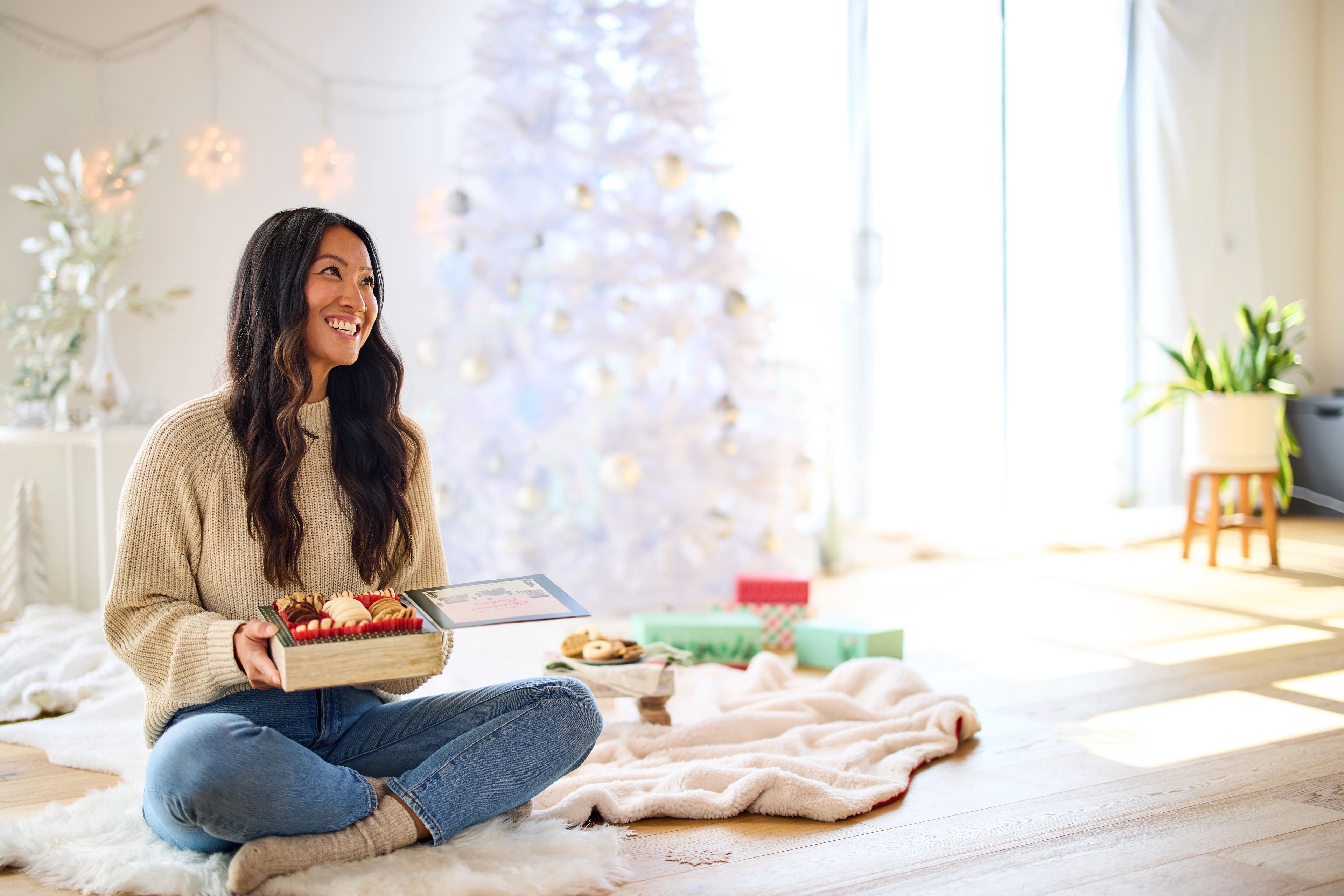 Woman sitting on floor holding a box of cookies.