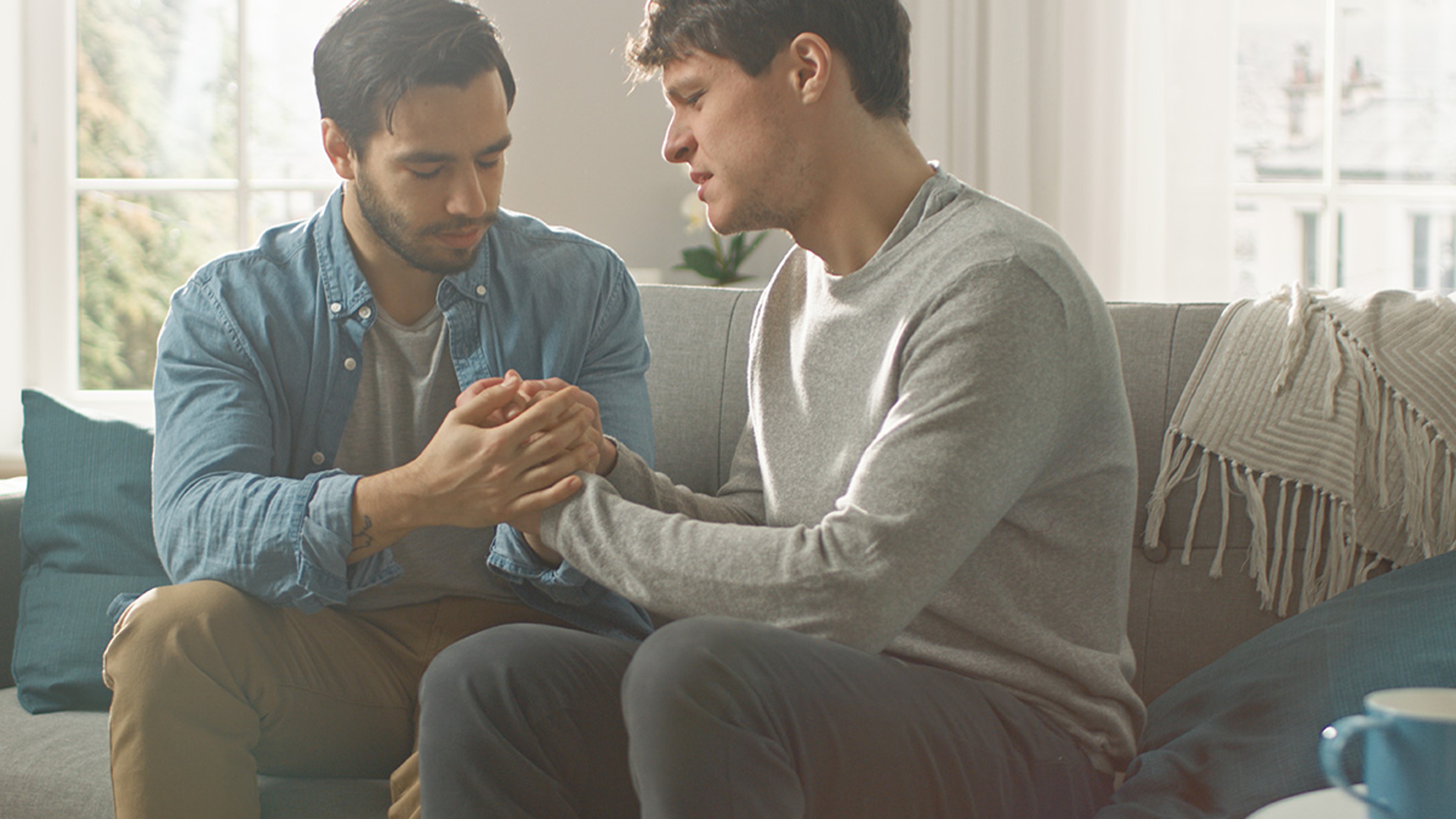 Couple sitting on the couch comforting each other.
