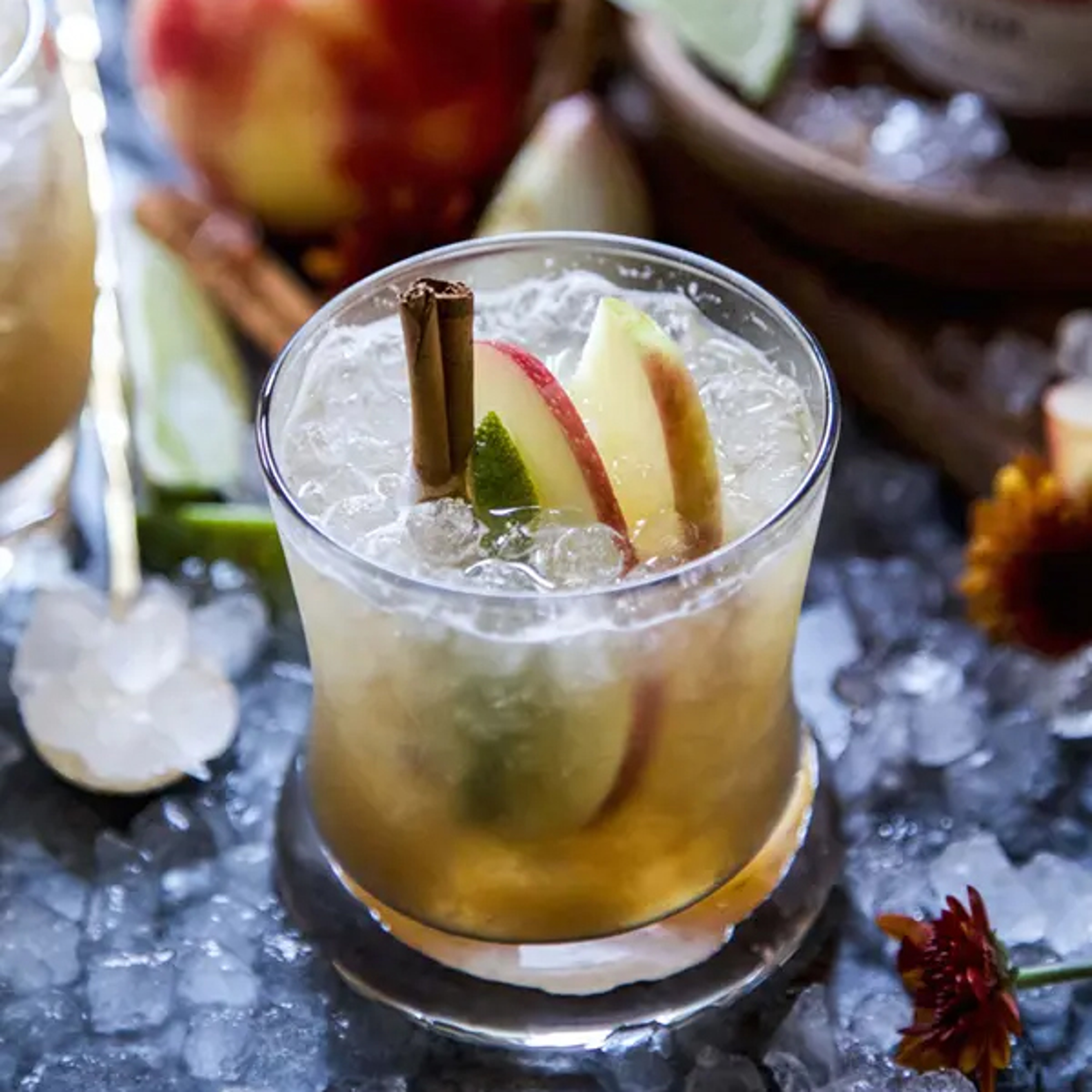 Apple butter cocktail with sliced apples and a stick of cinnamon.