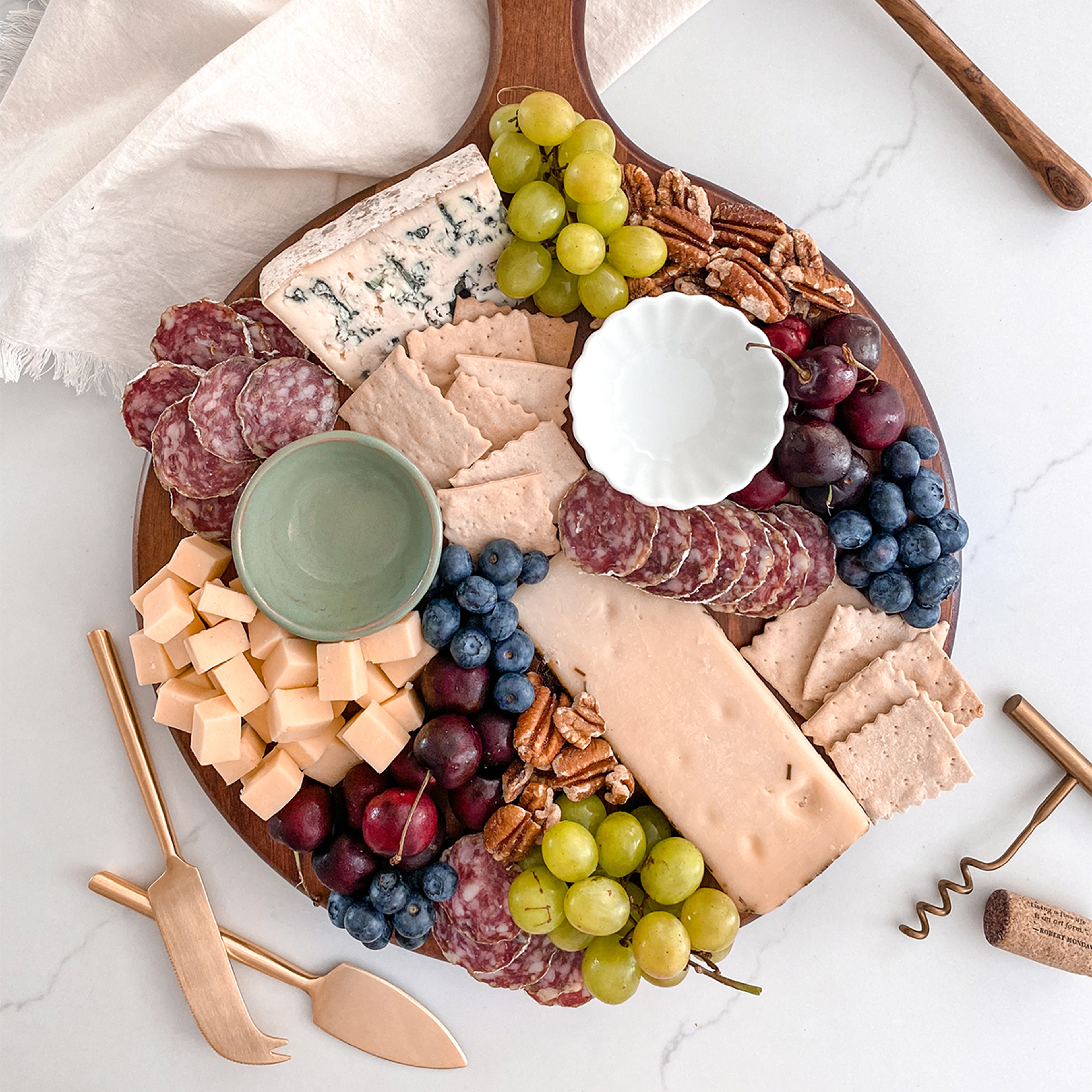 How to create a charcuterie board with cheese, meat, fruit, nuts, and other snacks.