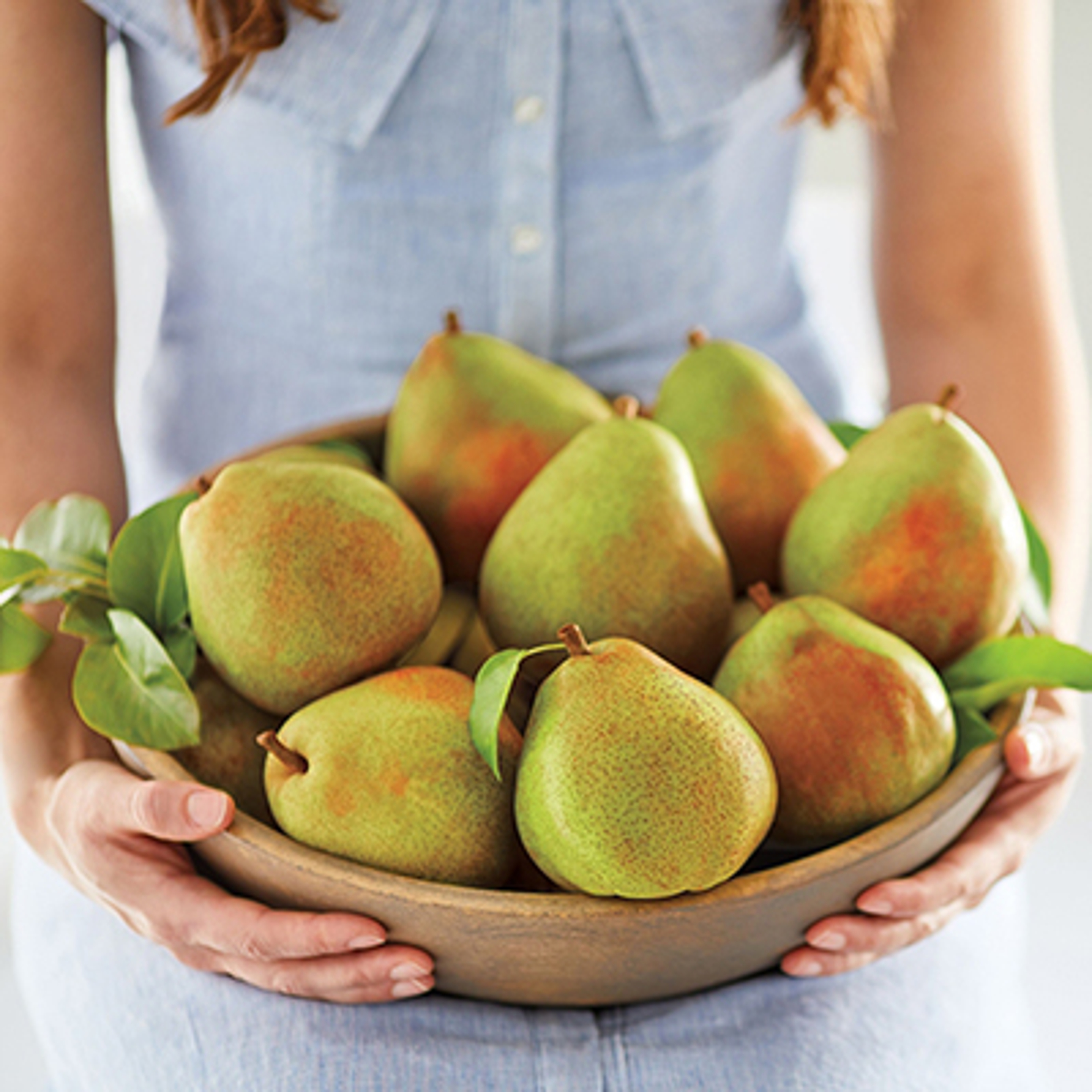 Woman holding a large bowl of pears.