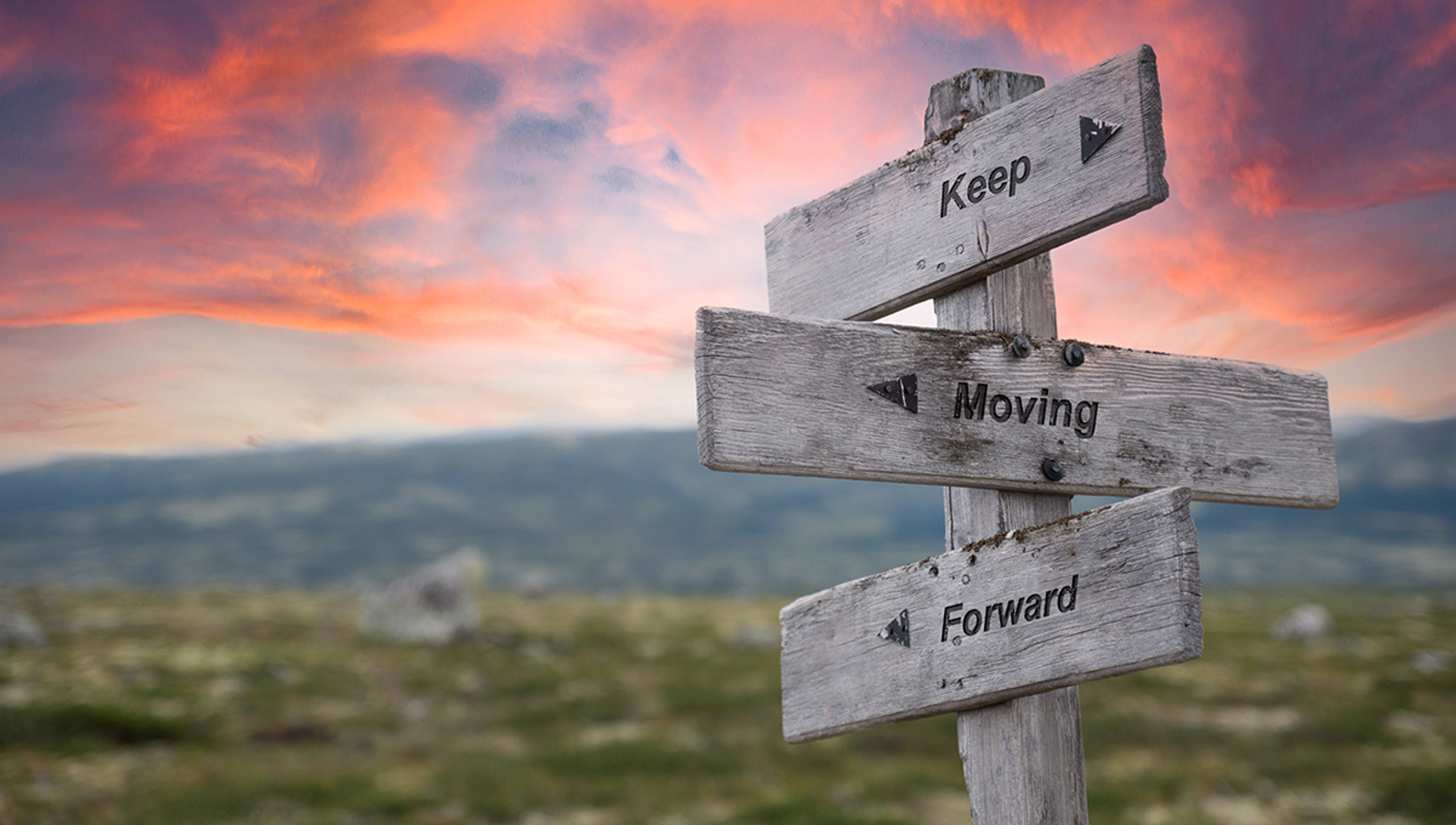 keep moving forward text engraved in wooden signpost outdoors in