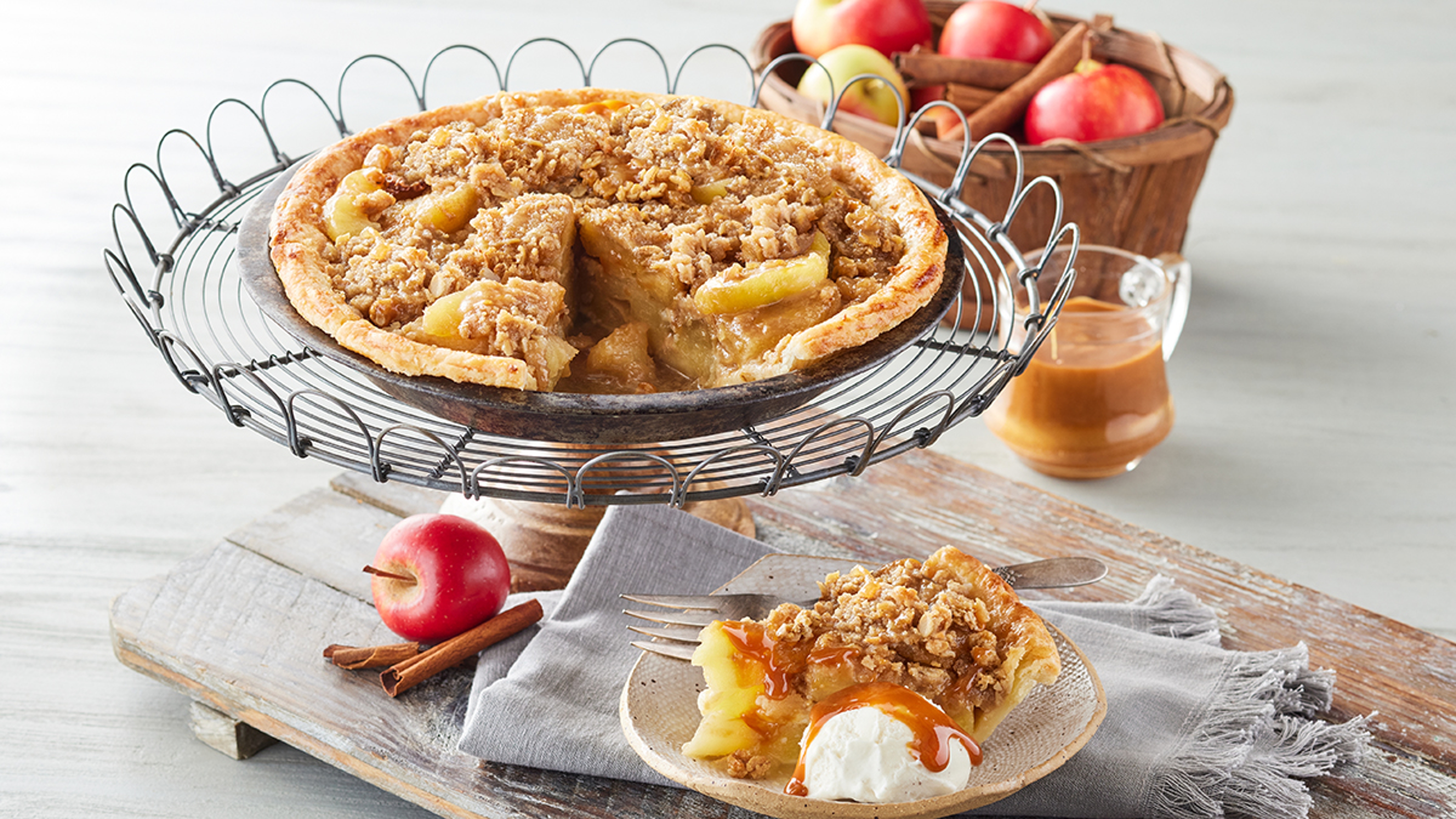 Fall flavors with a Dutch apple pie on a platter next to a basket of apples.