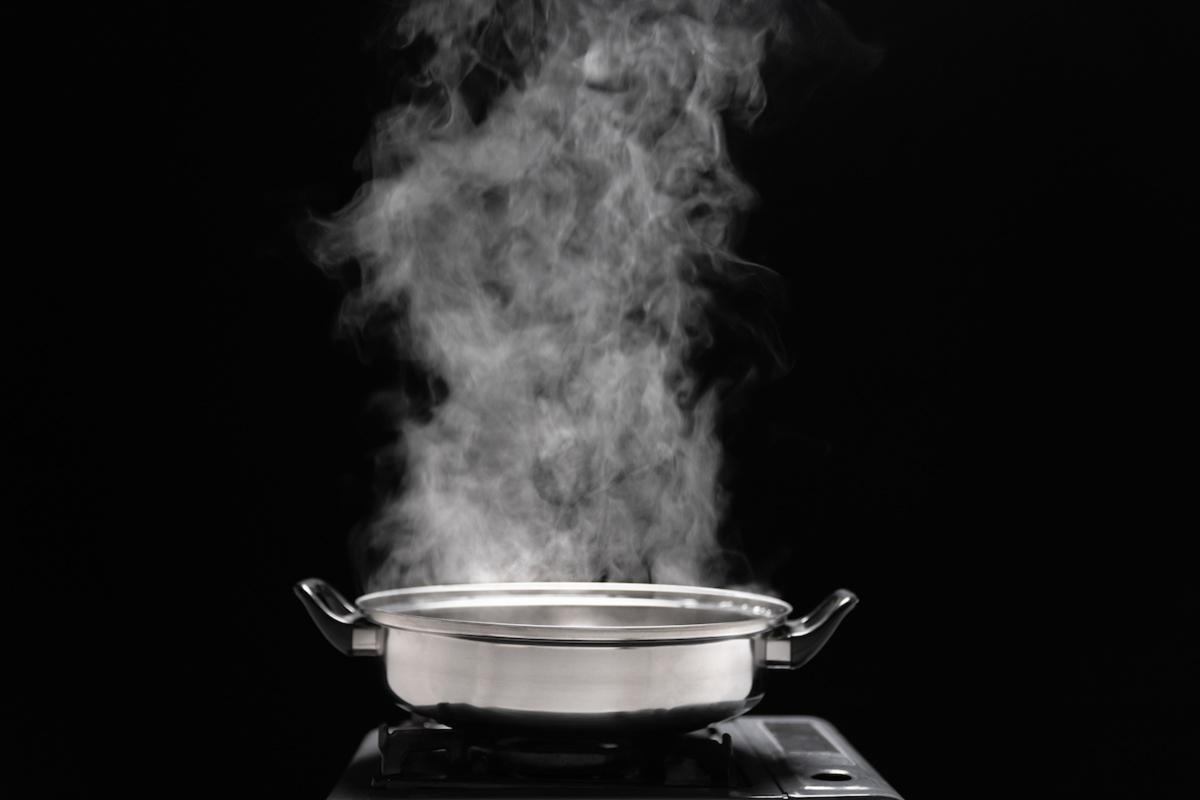 Article Cards Featured Image Steam over cooking pot in kitchen on dark background.