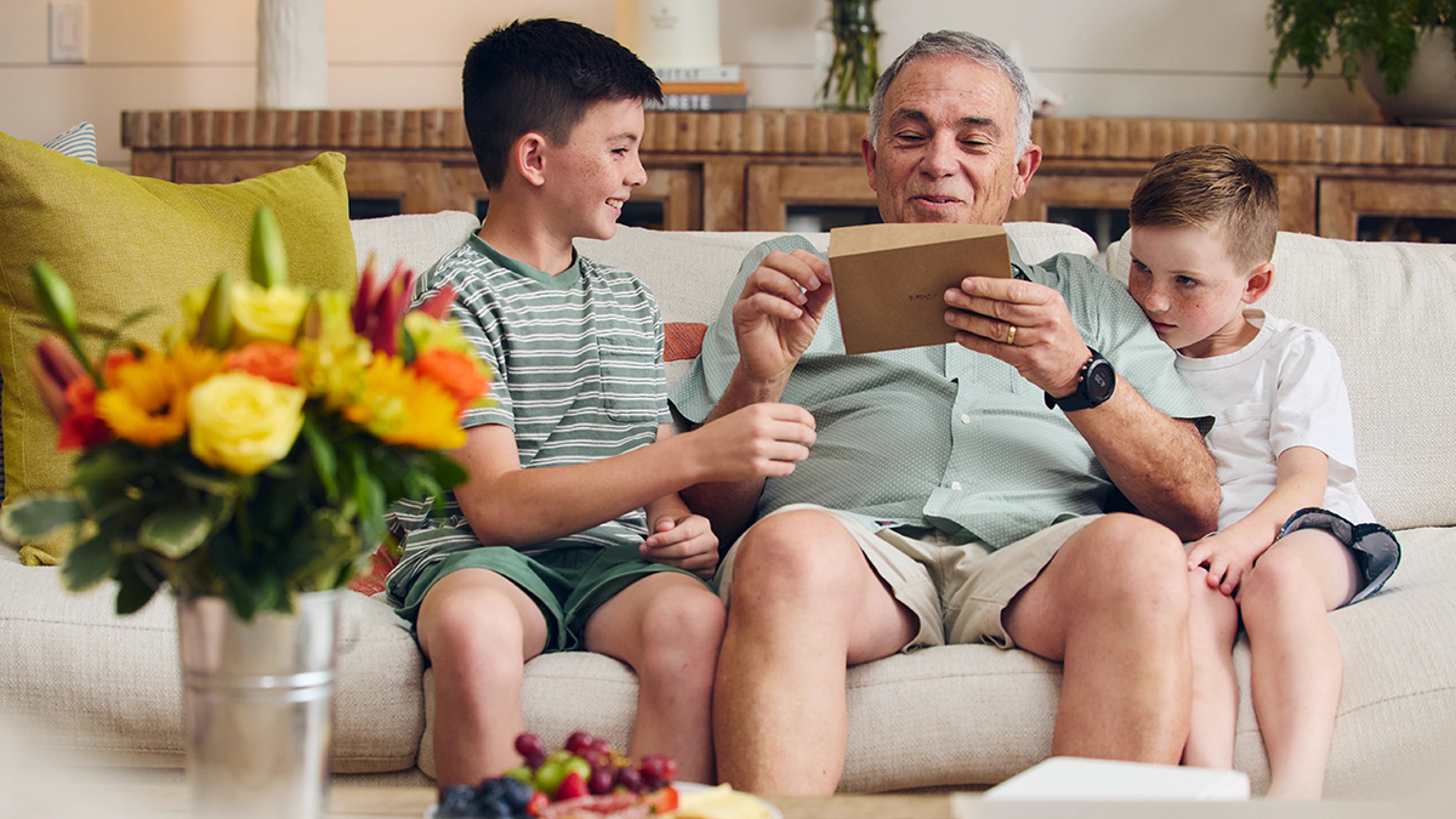 Two boys giving their grandfather a card.