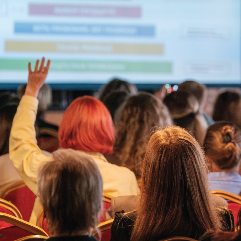 A woman in a group of people is raising her hand