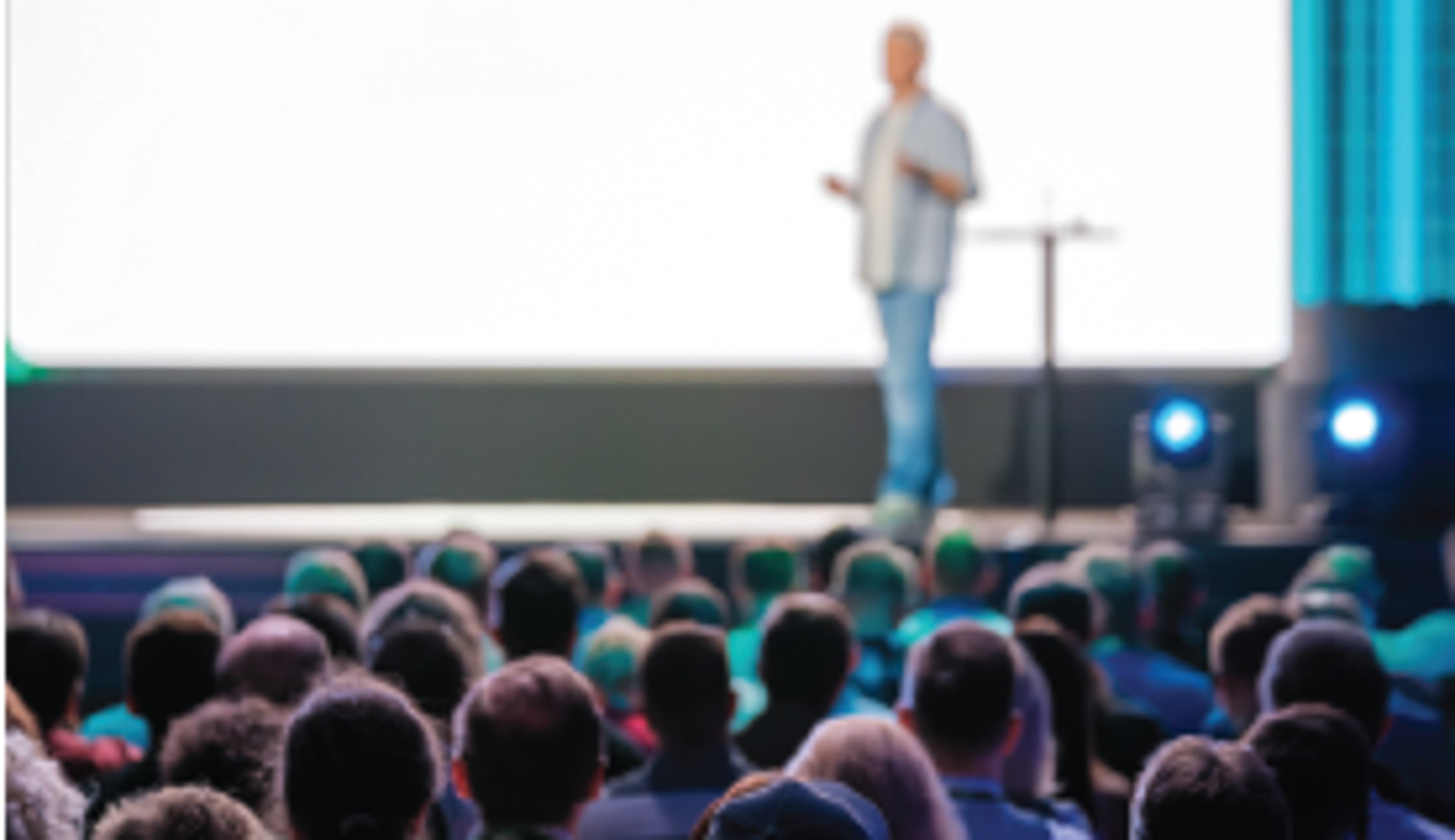 seated crowd listening to a speaker on stage