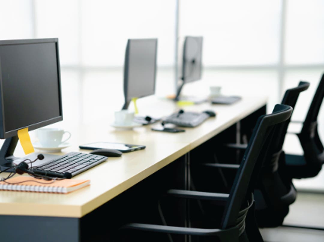 Angled view of three laptops sitting on top of a desk open-screened