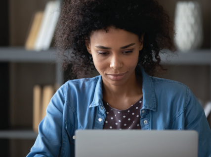woman sitting at a desk while looking at a laptop screen