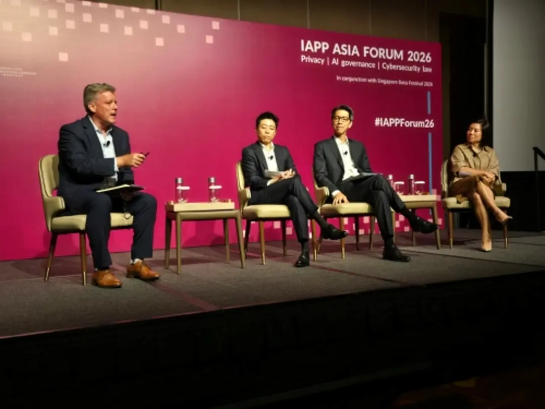 Four panelists are seated on stage during a discussion at the IAPP Asia Forum 2026. The panel takes place in front of a pink event backdrop, with chairs, side tables, and water bottles arranged across the stage.