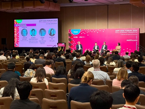 Conference attendees fill a large meeting room while a keynote panel is presented on stage at the IAPP Asia Forum 2026. A presentation screen displays panel speaker headshots and names, and the audience is seated facing the stage and screen.