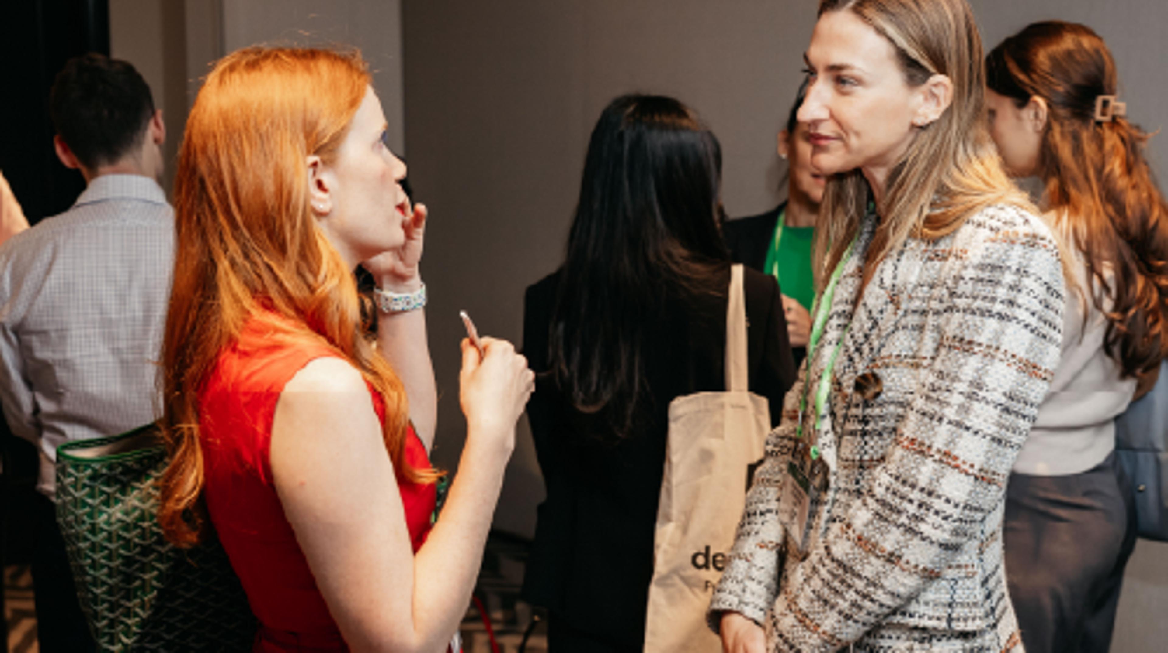 Two young women at an IAPP conference talk to each other about a shared interest.
