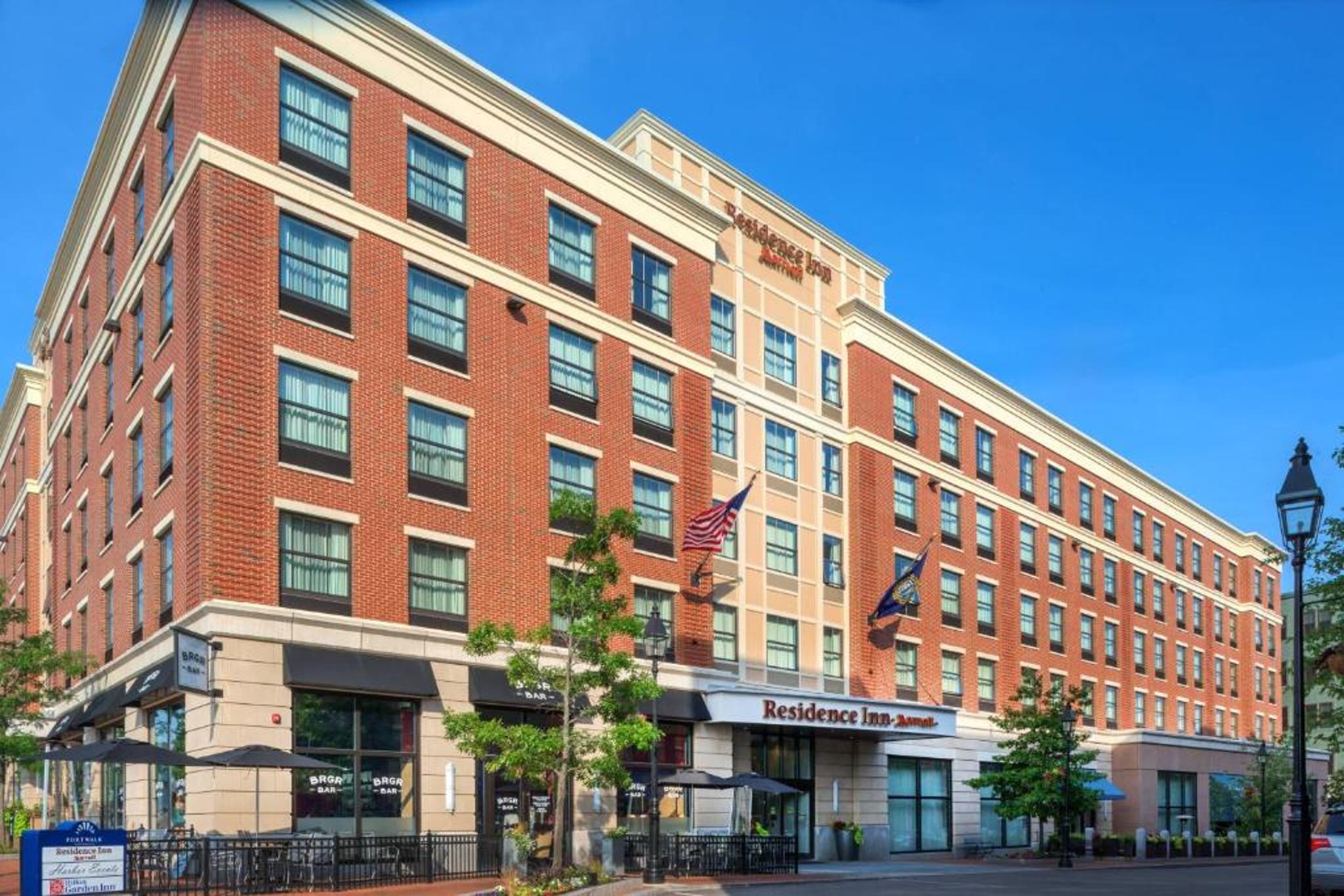 Residence Inn hotel with brick exterior, flags at entrance, and trees along the sidewalk.