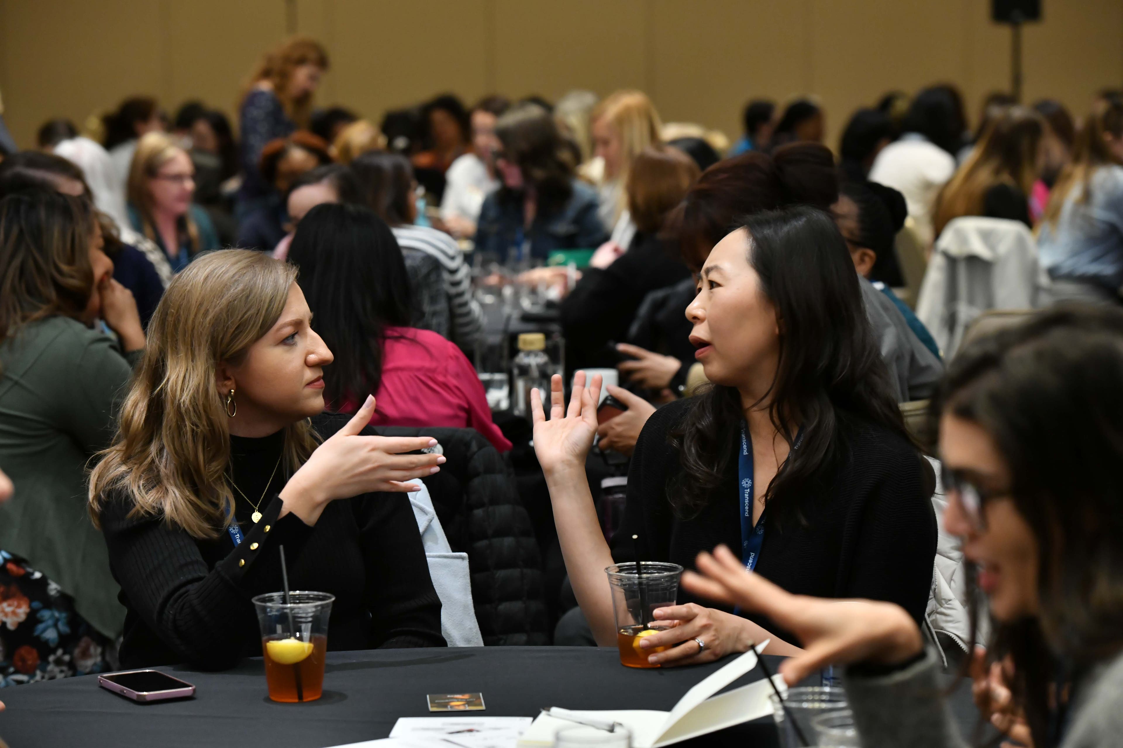 Two women talking to each other, they are gesturing with their hands