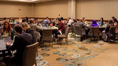 A room with multiple tables of people gathered for at a Diversity in Privacy section meetup