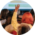 Image of a woman with pink hair raising her hand in front of a presentation