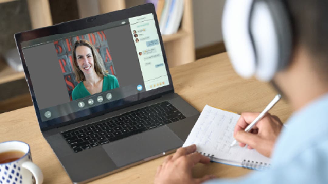 person at desk engaging in live online training on their laptop
