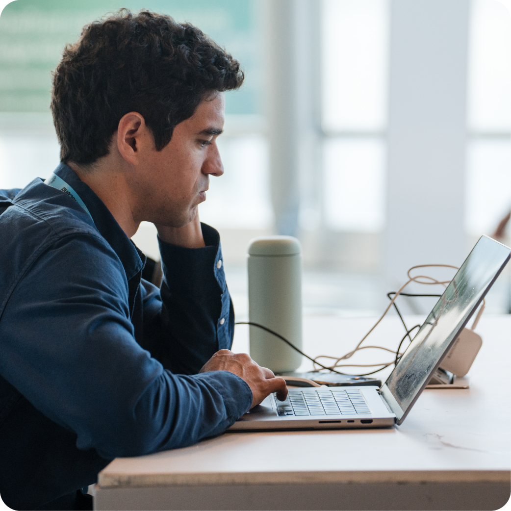 A man sitting at a desk viewing a video on his laptop
