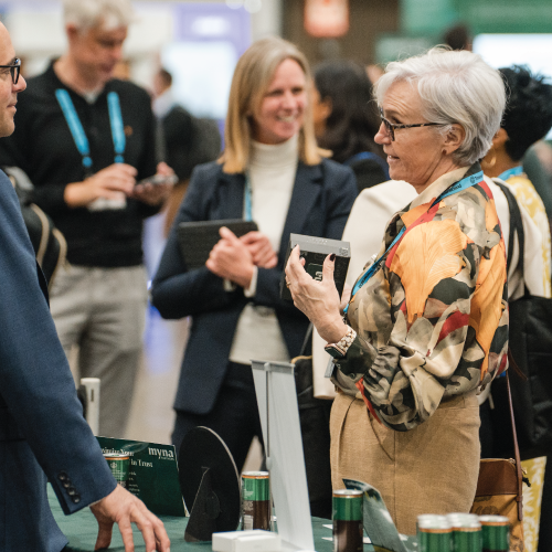 A woman standing and reaching across a table to shake someone's hand