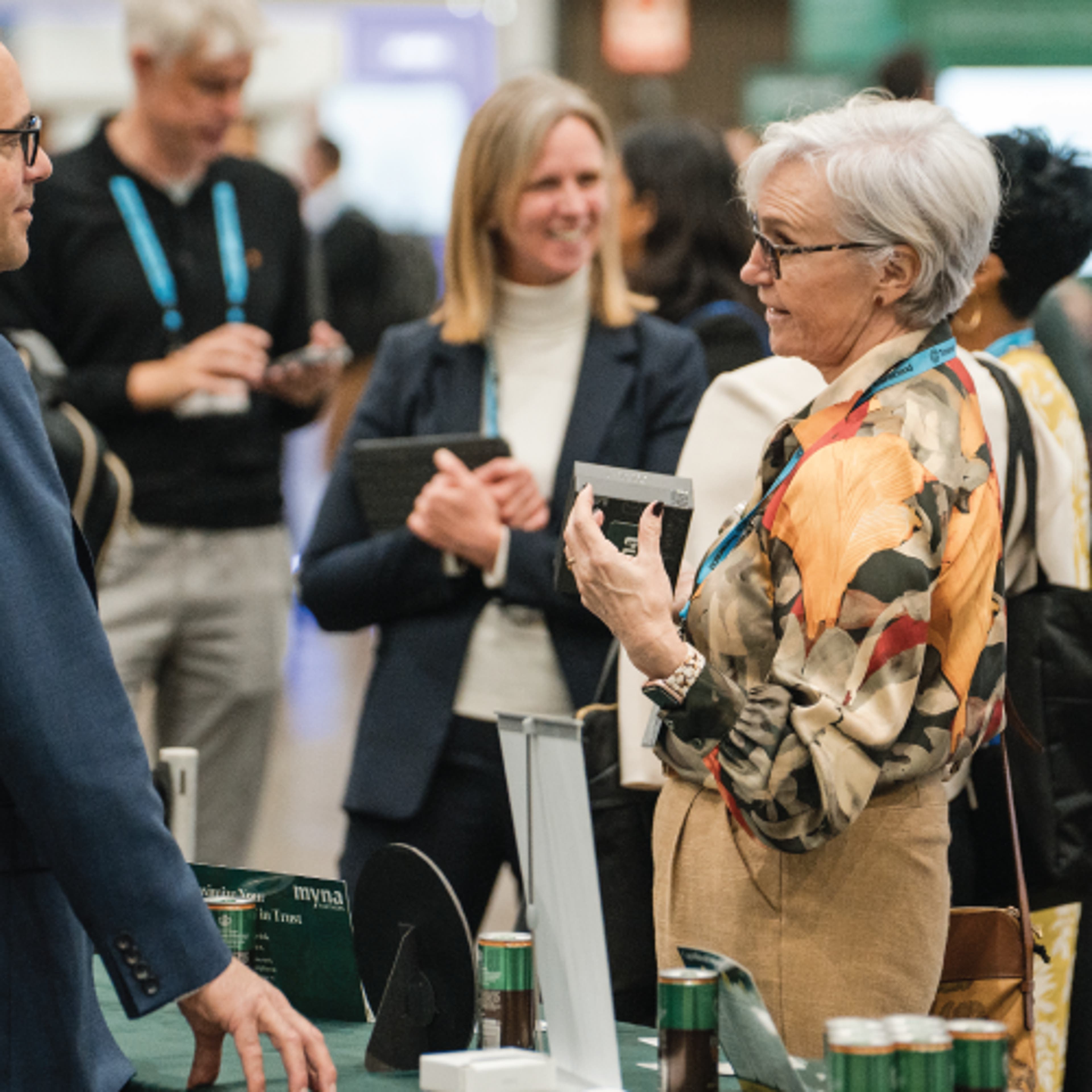 A woman standing and reaching across a table to shake someone's hand