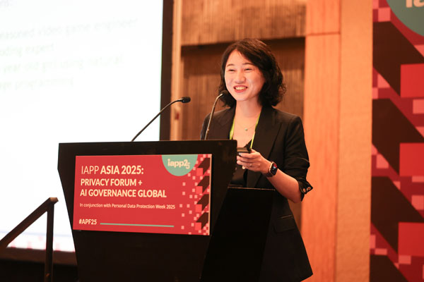 Networking area with attendees standing and talking near a booth featuring a blue display wall with company branding and promotional materials.