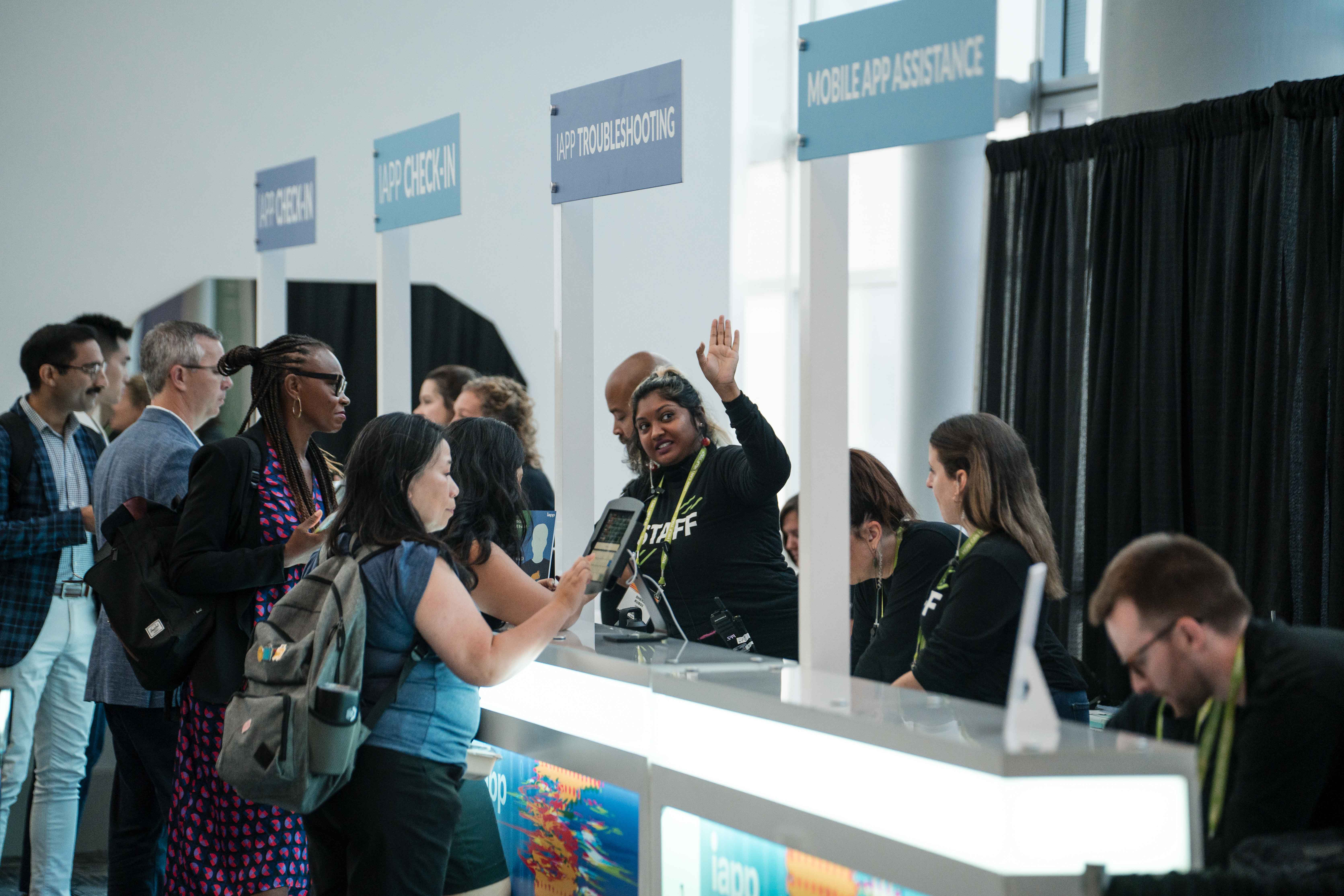 A young woman at a booth at a conference assisting an attendee