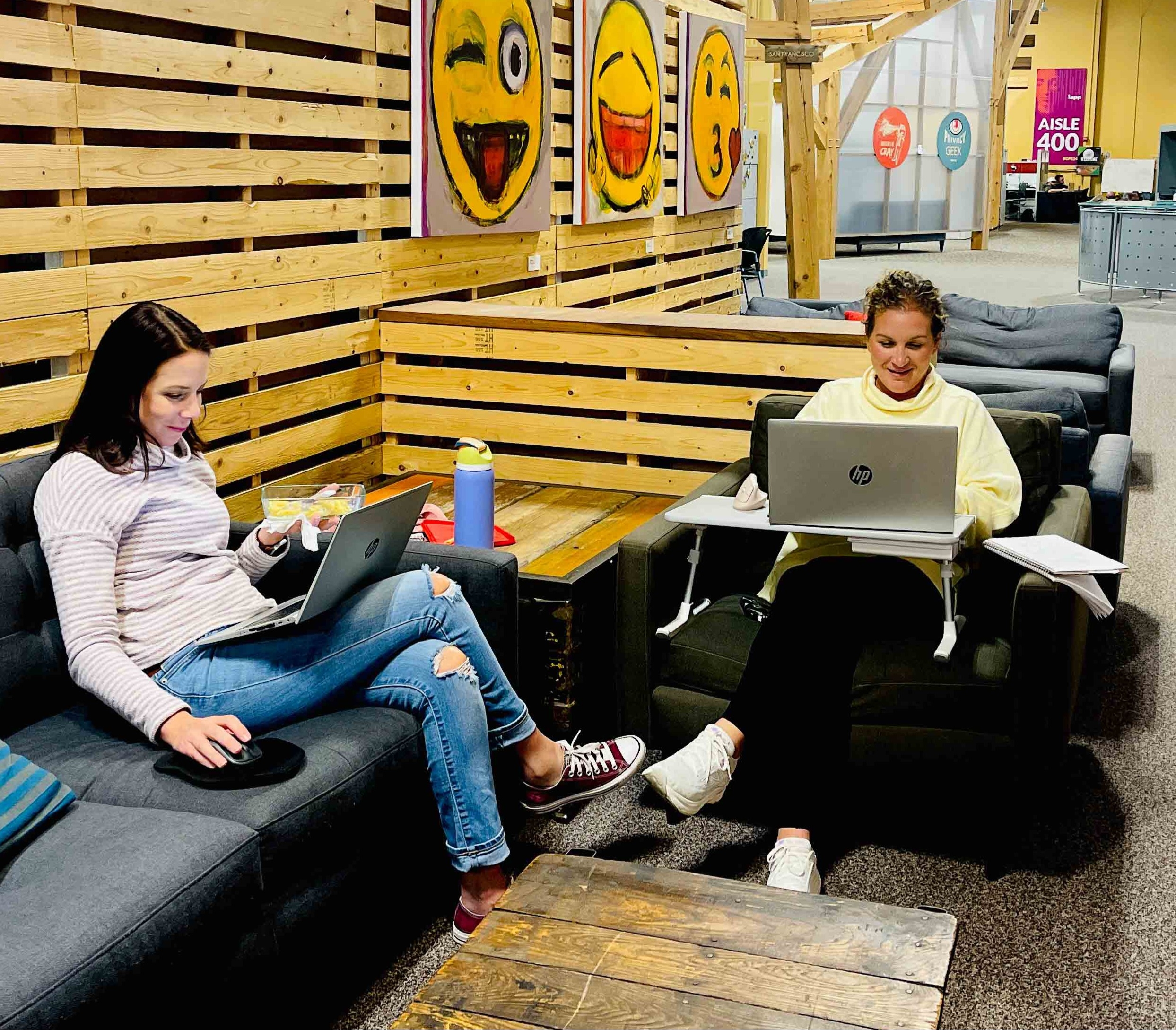 Two women sitting on couches at the IAPP HQ working on laptops