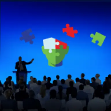 Graphic of a person speaking in front of people and puzzle pieces floating in the air.