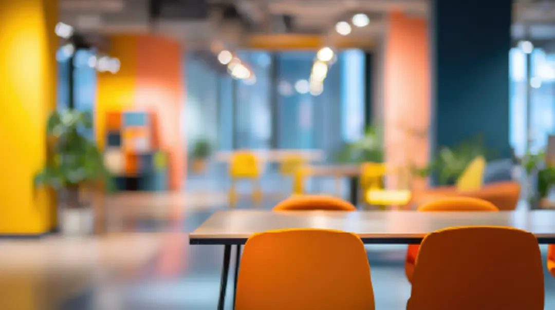 A table in chairs in an office. The focus is on the table and chairs while the background is out of focus.