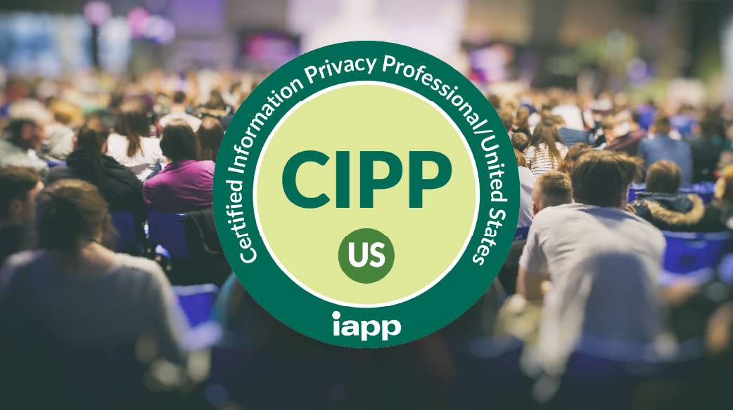 Large green and light yellow circular badge with the text “Certified Information Privacy Professional United States” and the IAPP logo around the edge. “CIPP” in bold letters and a US in a green circle located in the center of the badge. The badge is overlaid on a blurred background of a crowded conference audience seated in rows.