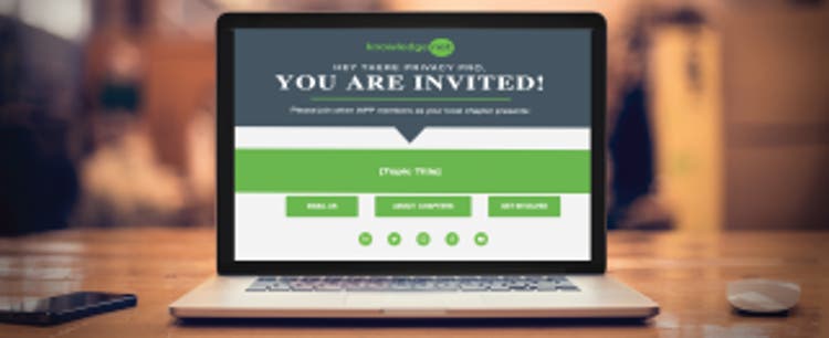 A laptop sits on a wooden table, backlit by out-of-focus warm lighting. The laptop screen is open and illuminates a KnowledgeNet meeting invitation on the display.