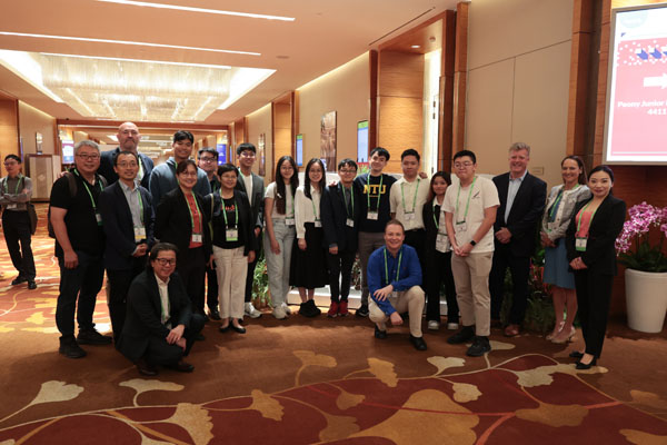 Close-up of a panel discussion with a person speaking into a microphone at a table with water glasses and documents.